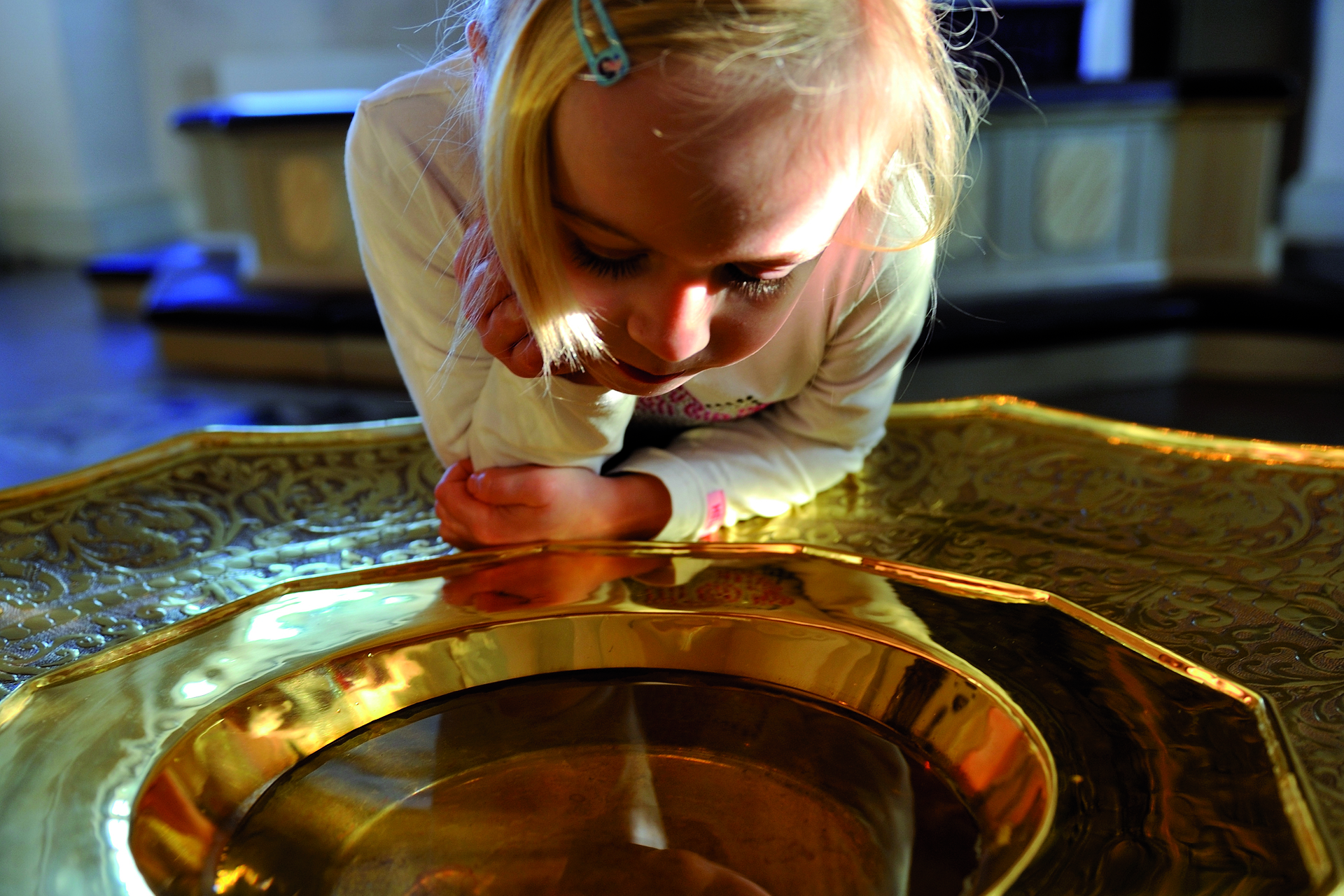 Barn tittar intresserat ner i en dopfunt