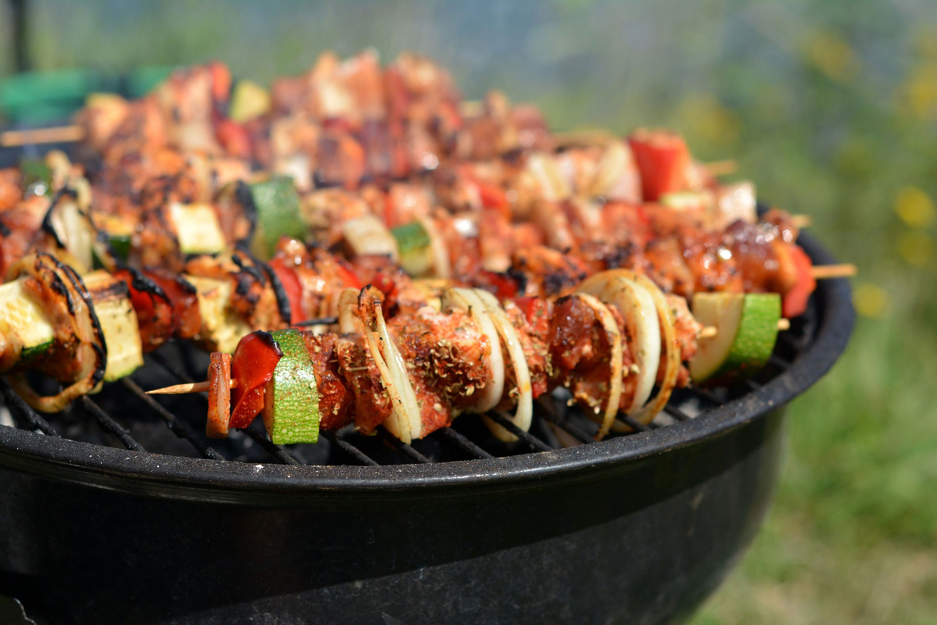 Spett med kött och grönsaker som tillagas på en varm grill.