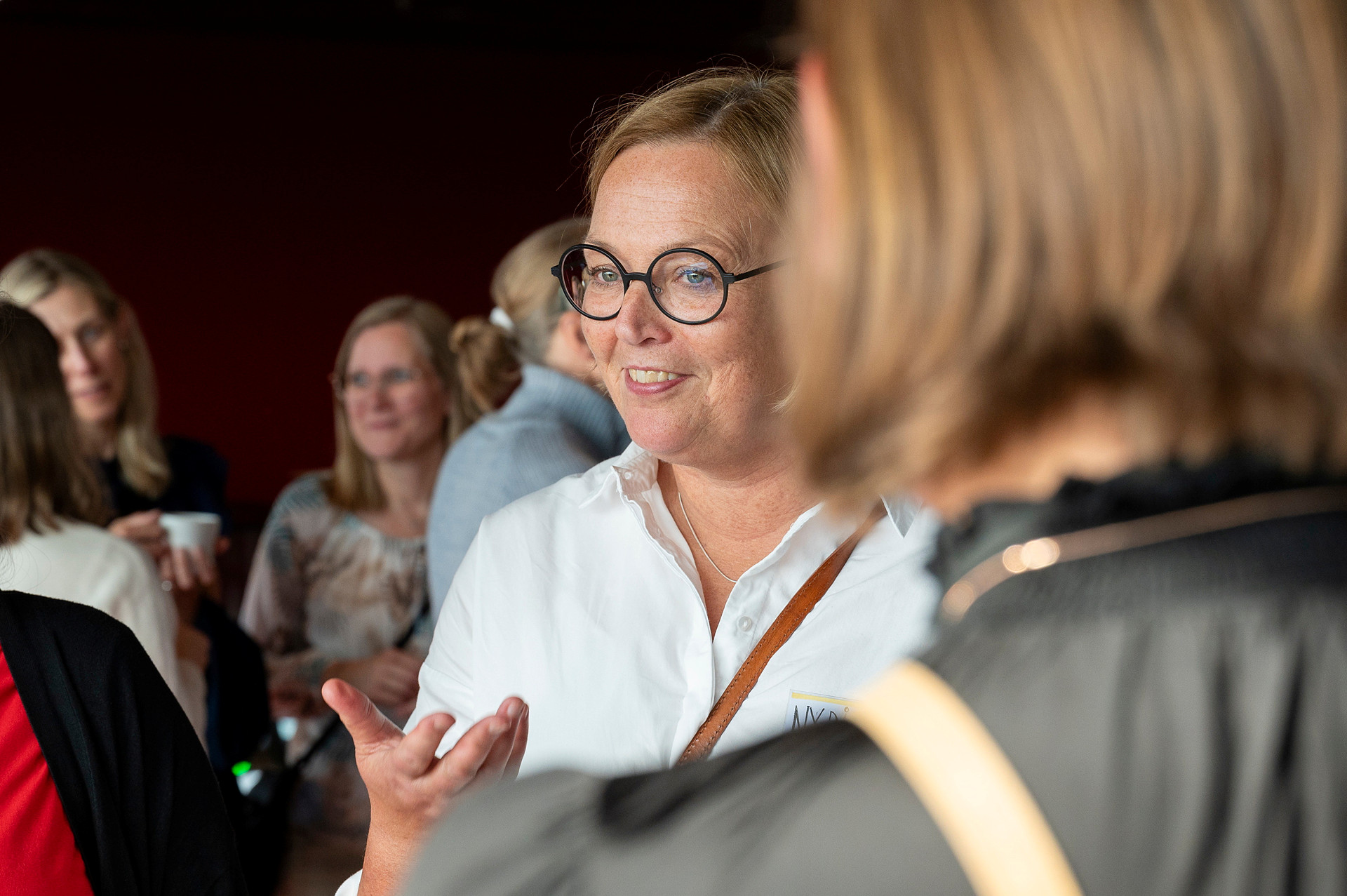 Generalsekreteraren står i en folksamling och talar med några personer.