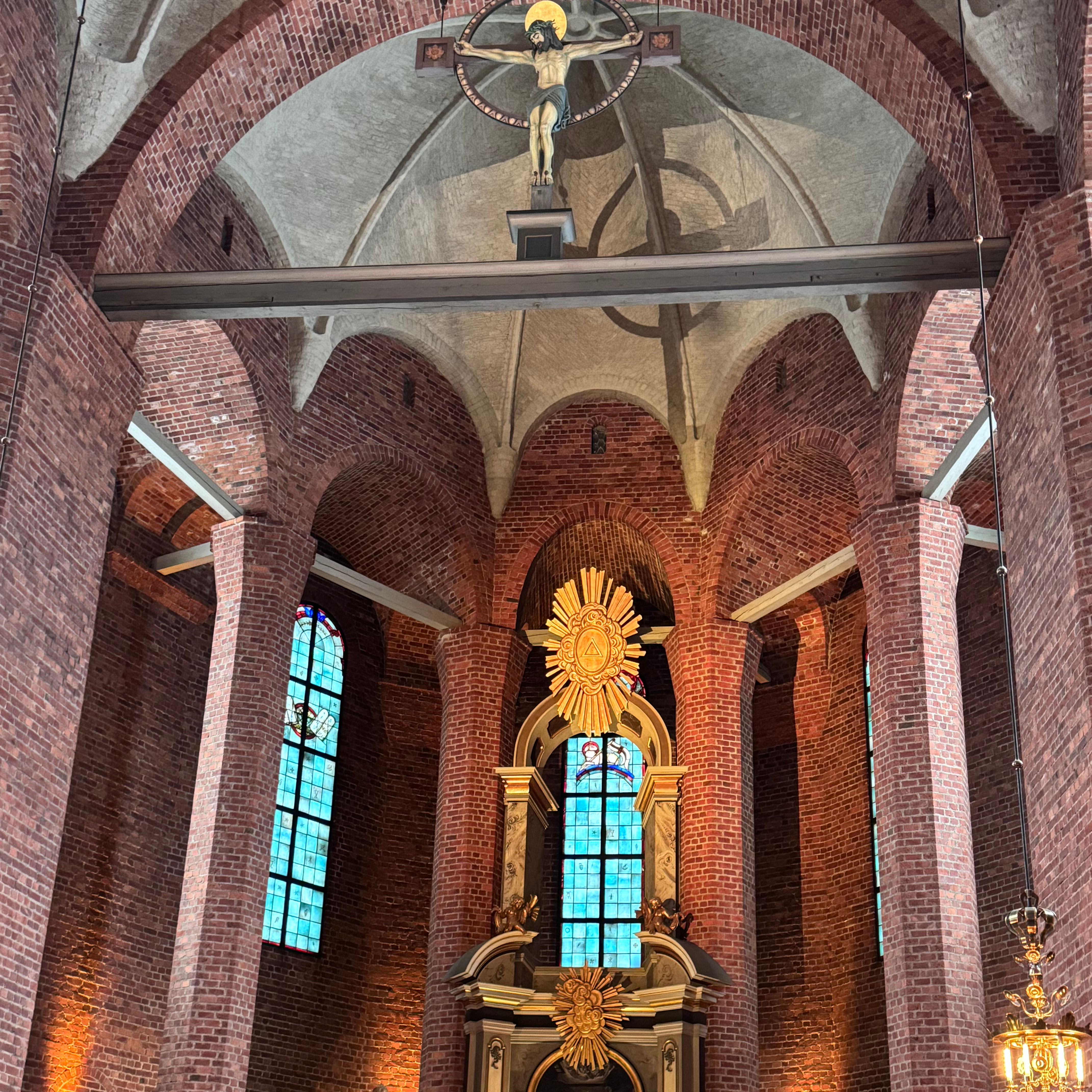 Ett kyrkorum med pelare och fönster. Ett krucifix i taket.