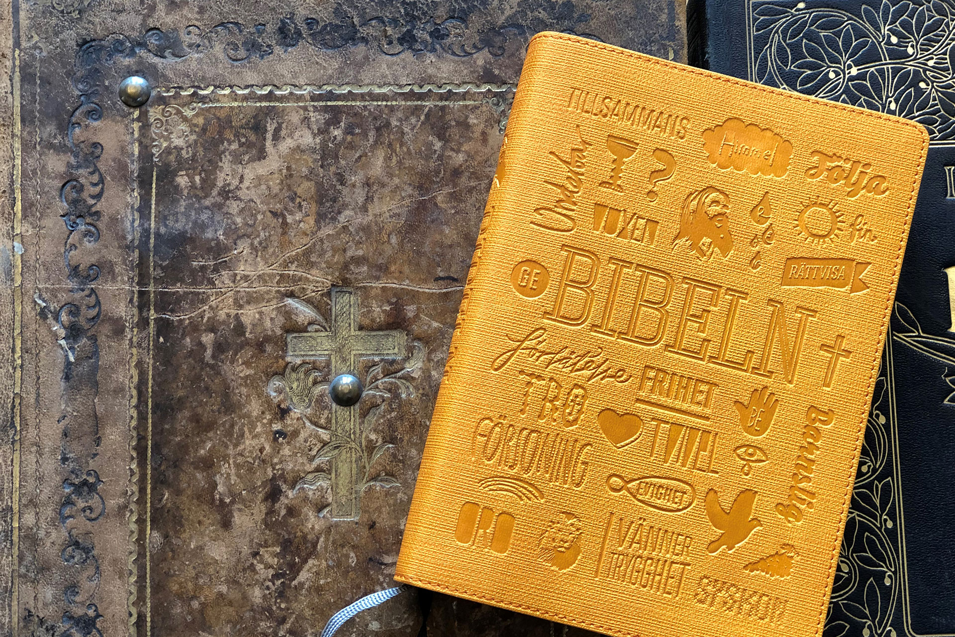 Modern orange bibel på en läderinbunden äldre bibel