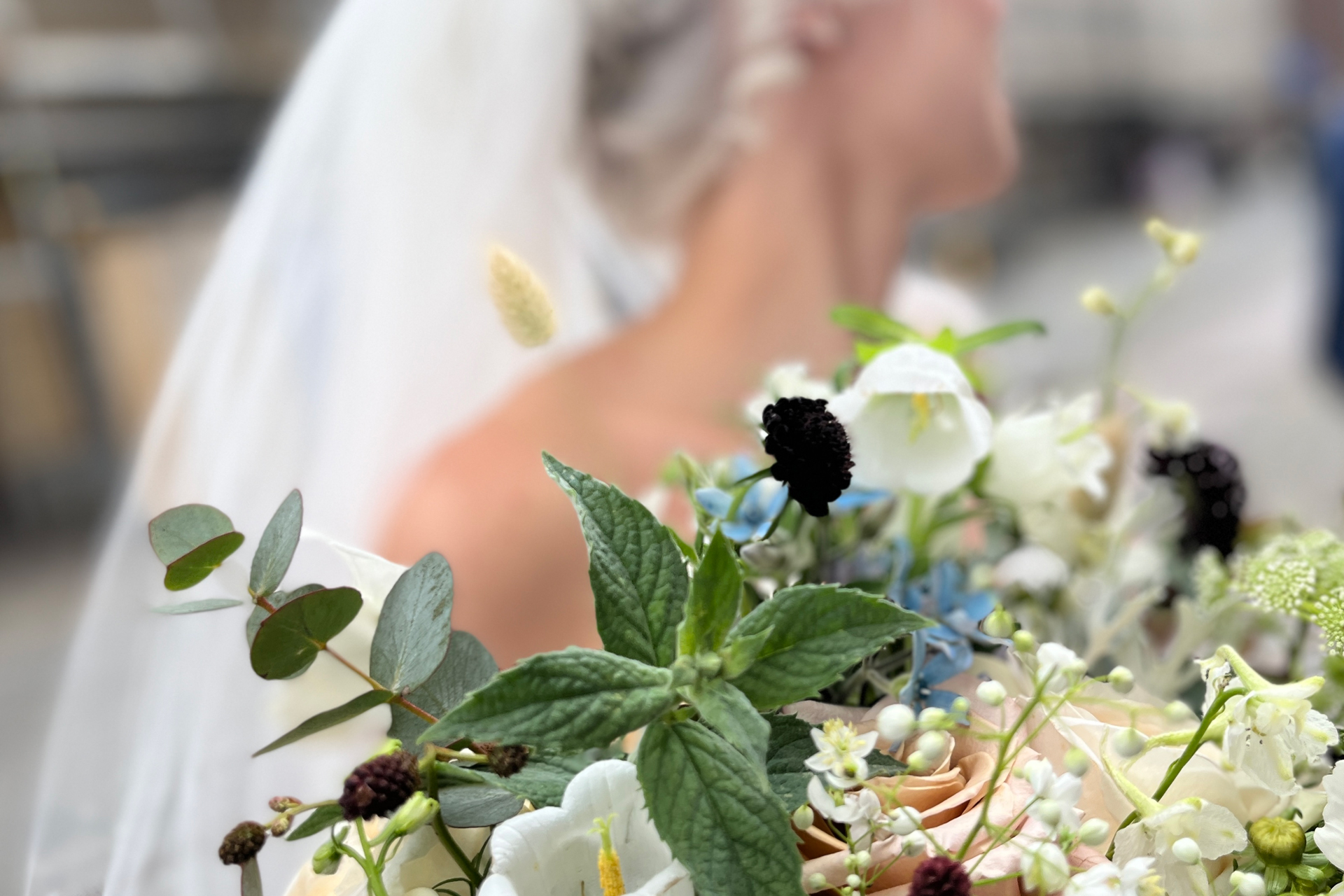Oskarp brud i slöja som vänder sig bort med blombukett i fokus.