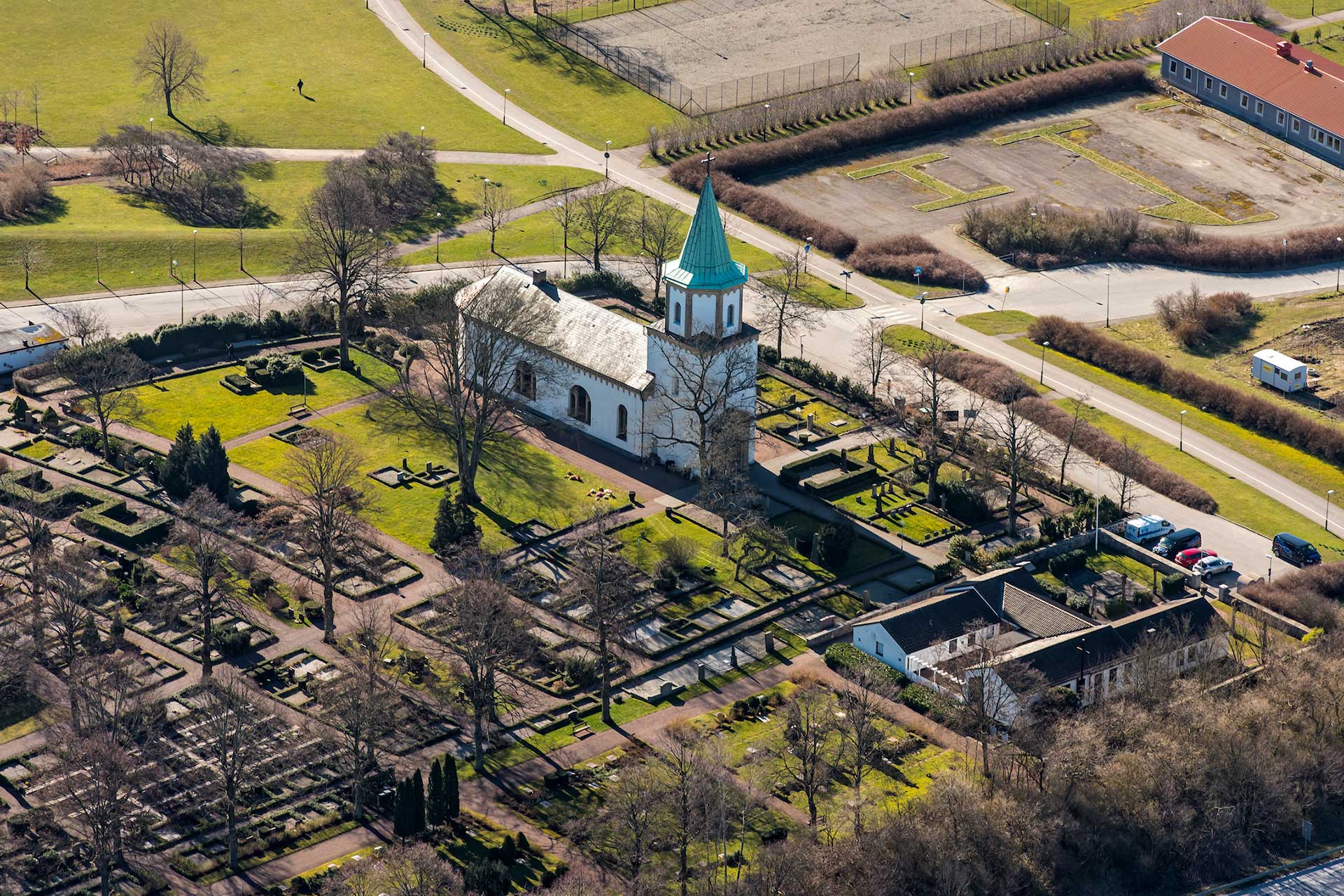 Flygfoto över Västra Skrävlinge kyrka i vårljus.
