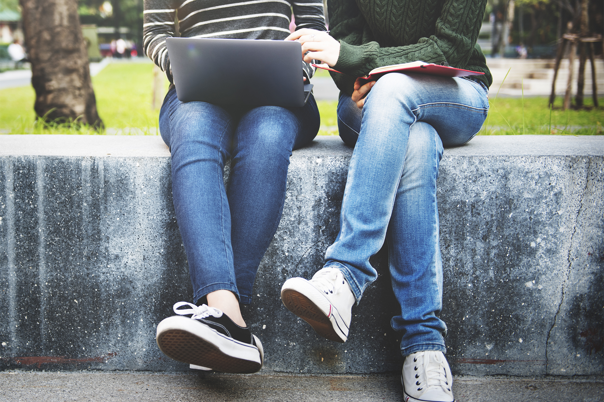 Två personer sitter på en mur där bara underkroppen syns