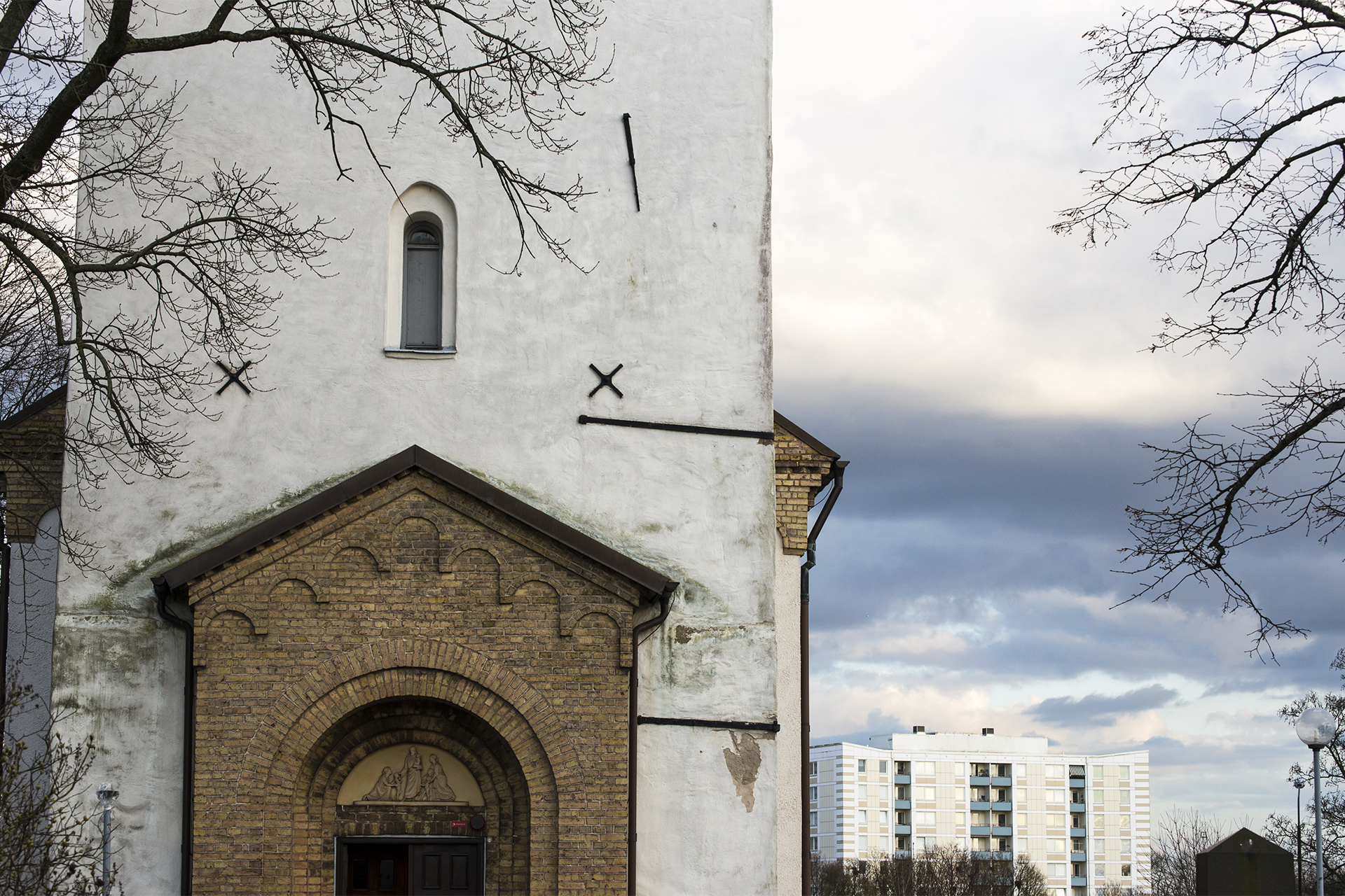 Ingång till kyrka med höghus i bakgrunden