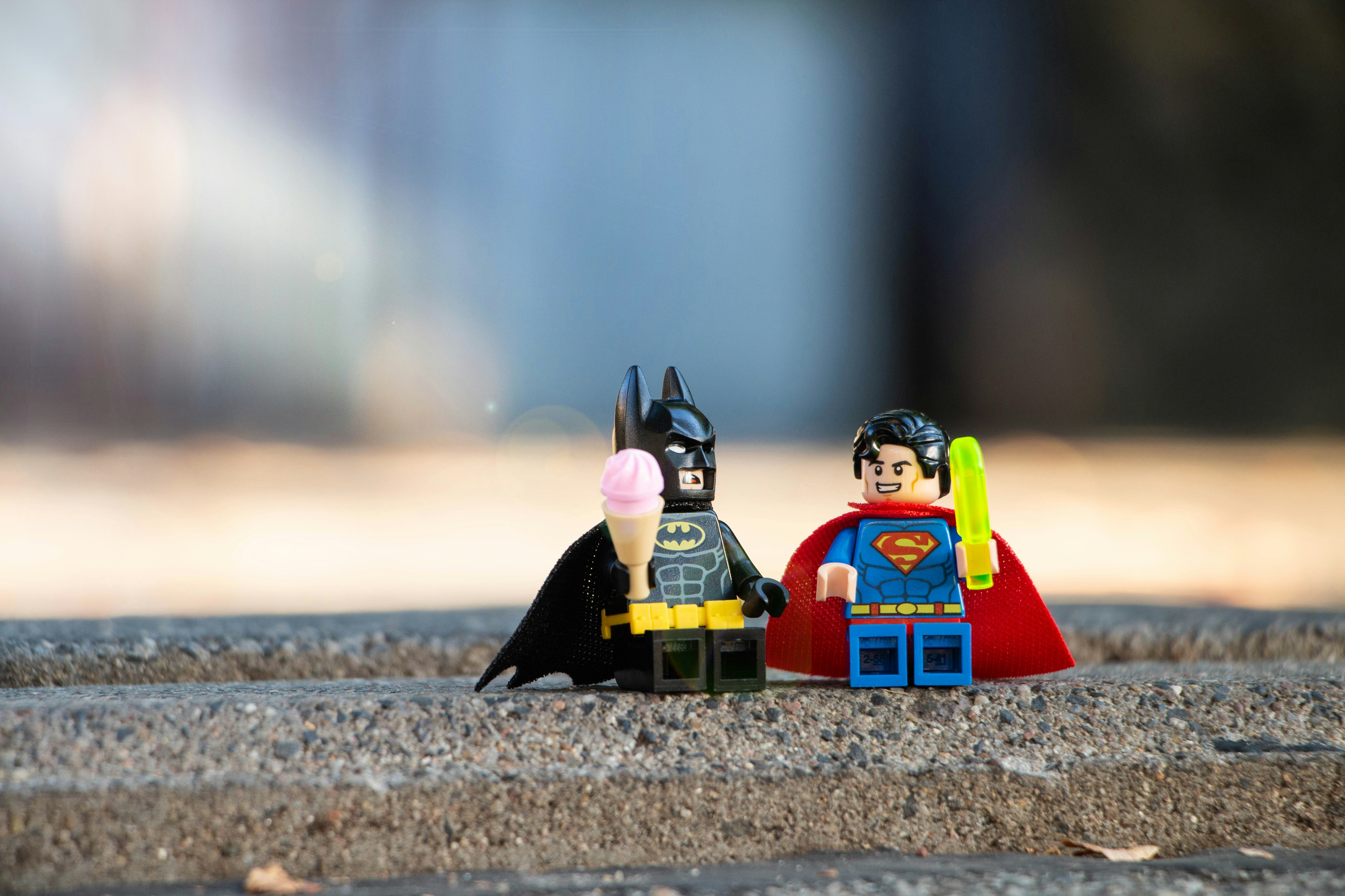 Två legogubbar föreställande Batman och Stålmannen håller i varsin legoglass.