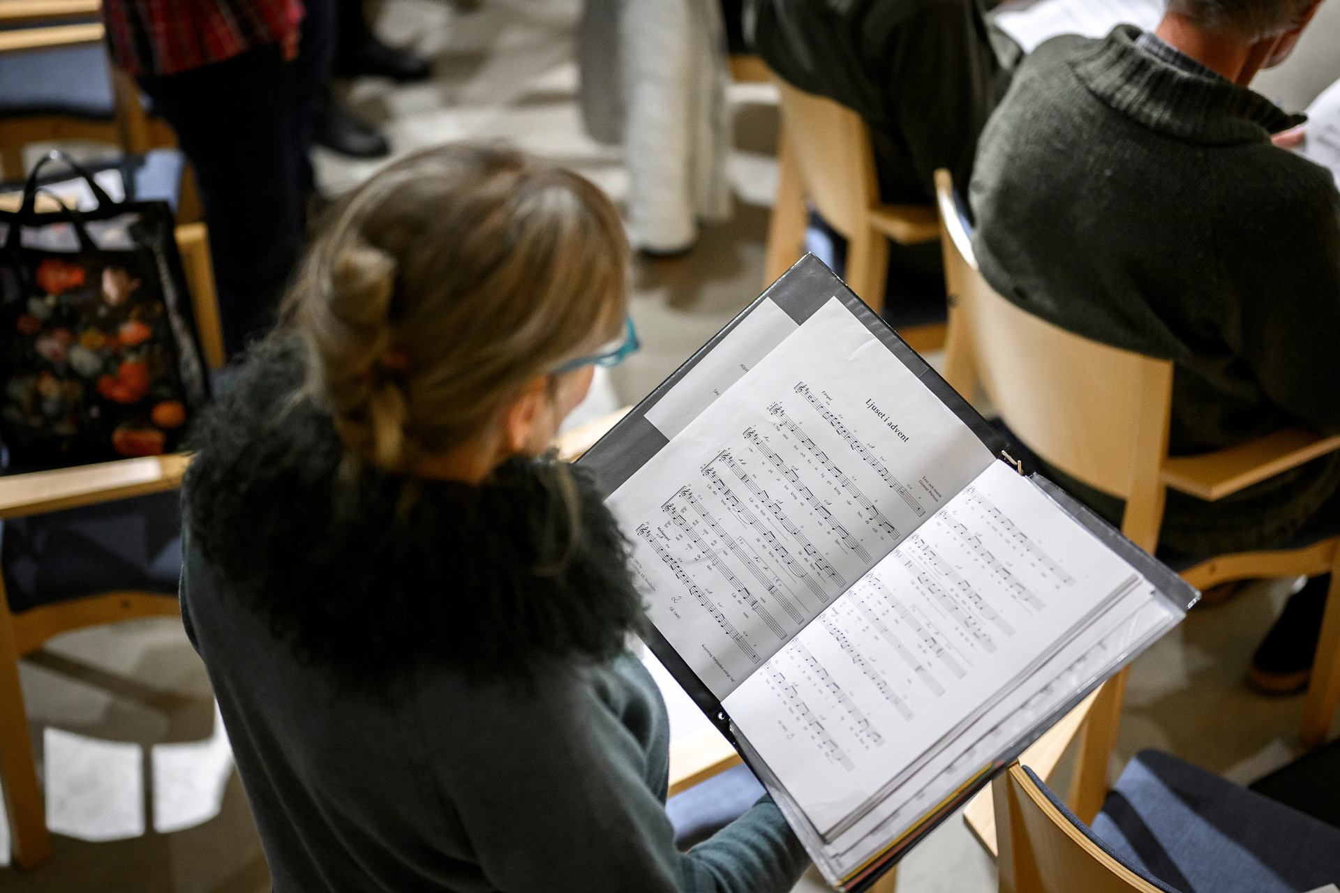 Kvinna fotat uppifrån som tittar ner i en pärm med noter. 