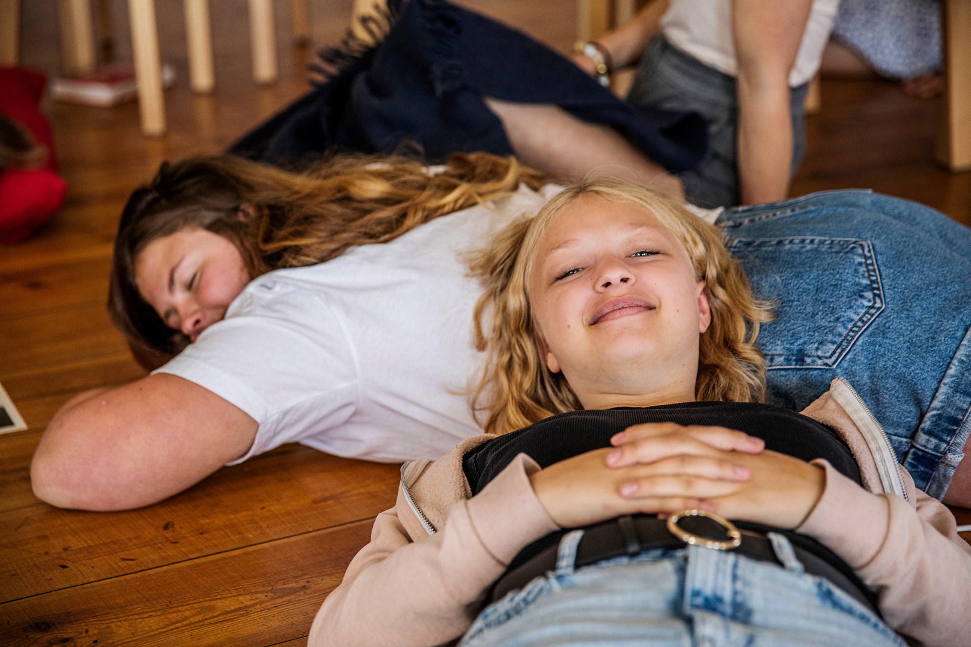 På bilden ser du glada ungdomar som vilar på golvet