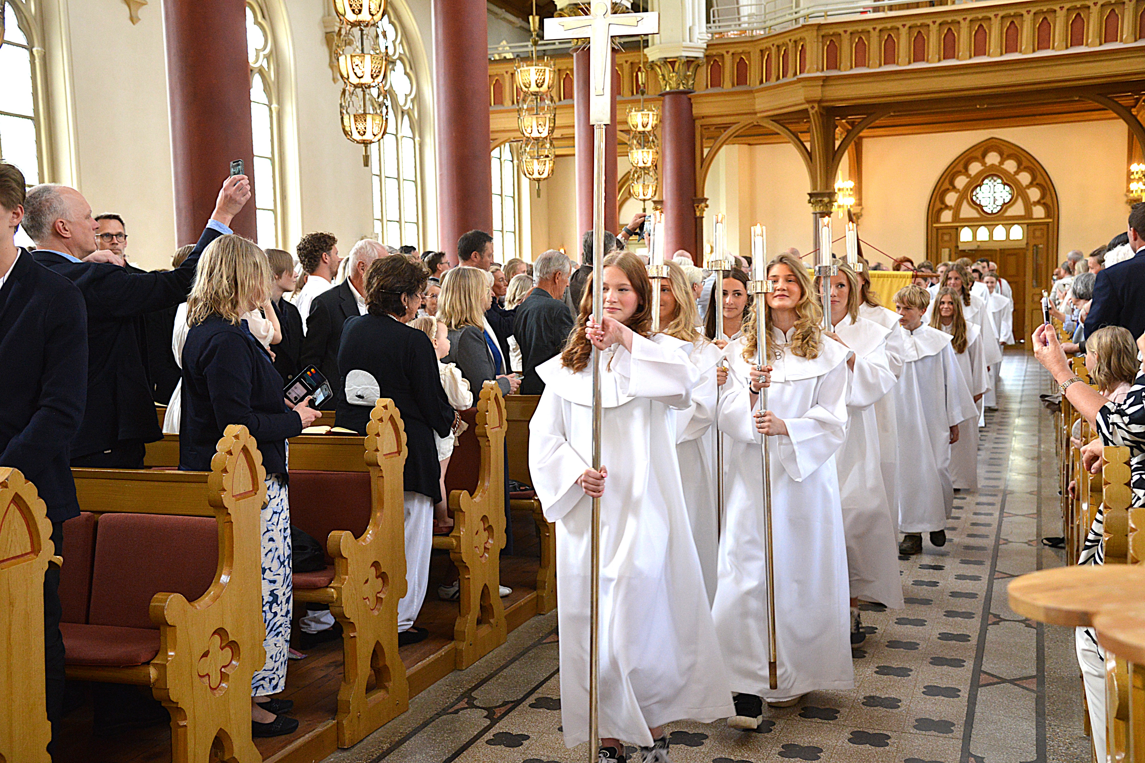 En grupp ungdomar vandrar in i en kyrka för konfirmation
