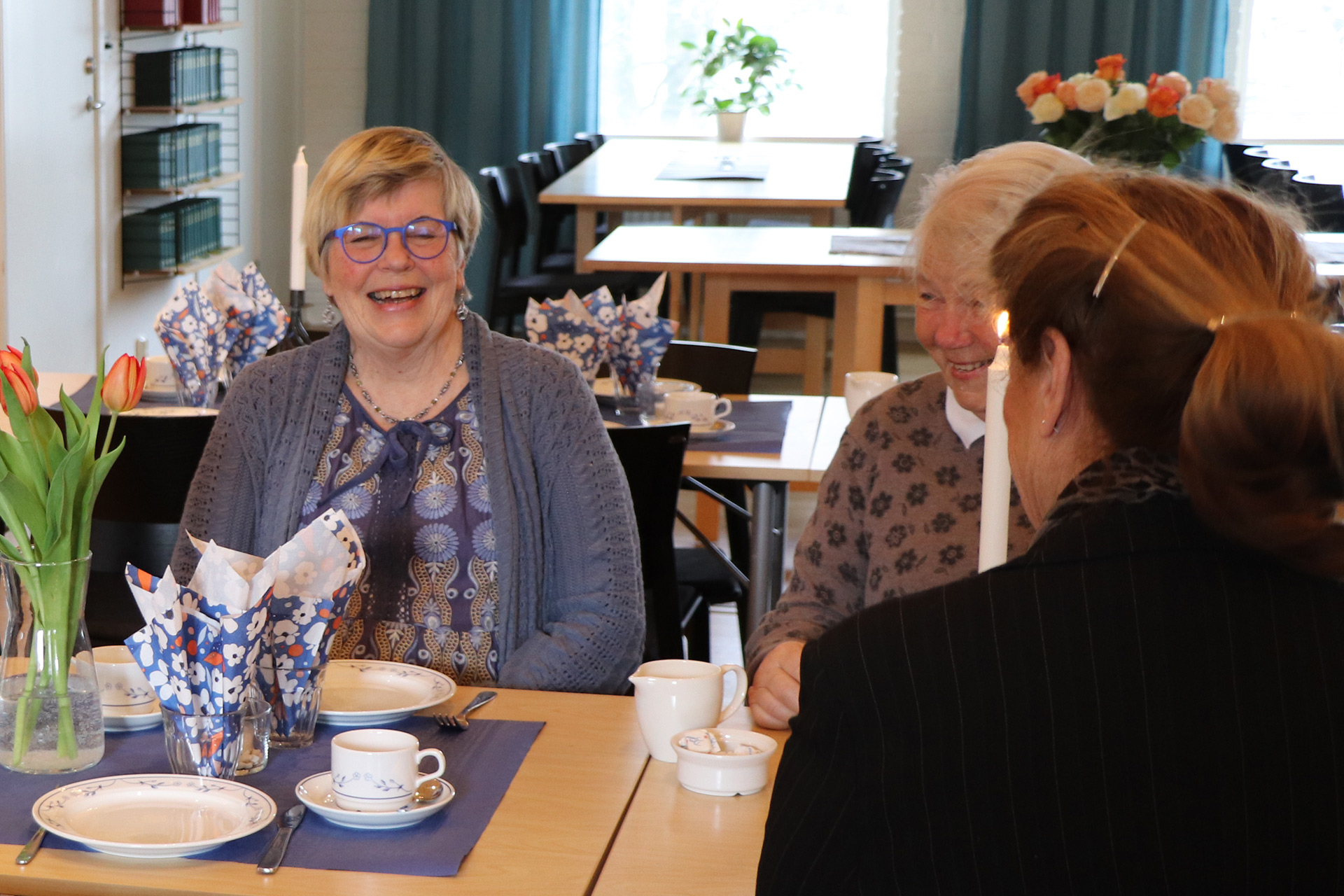 Personer sitter runt ett dukat bord och skrattar.