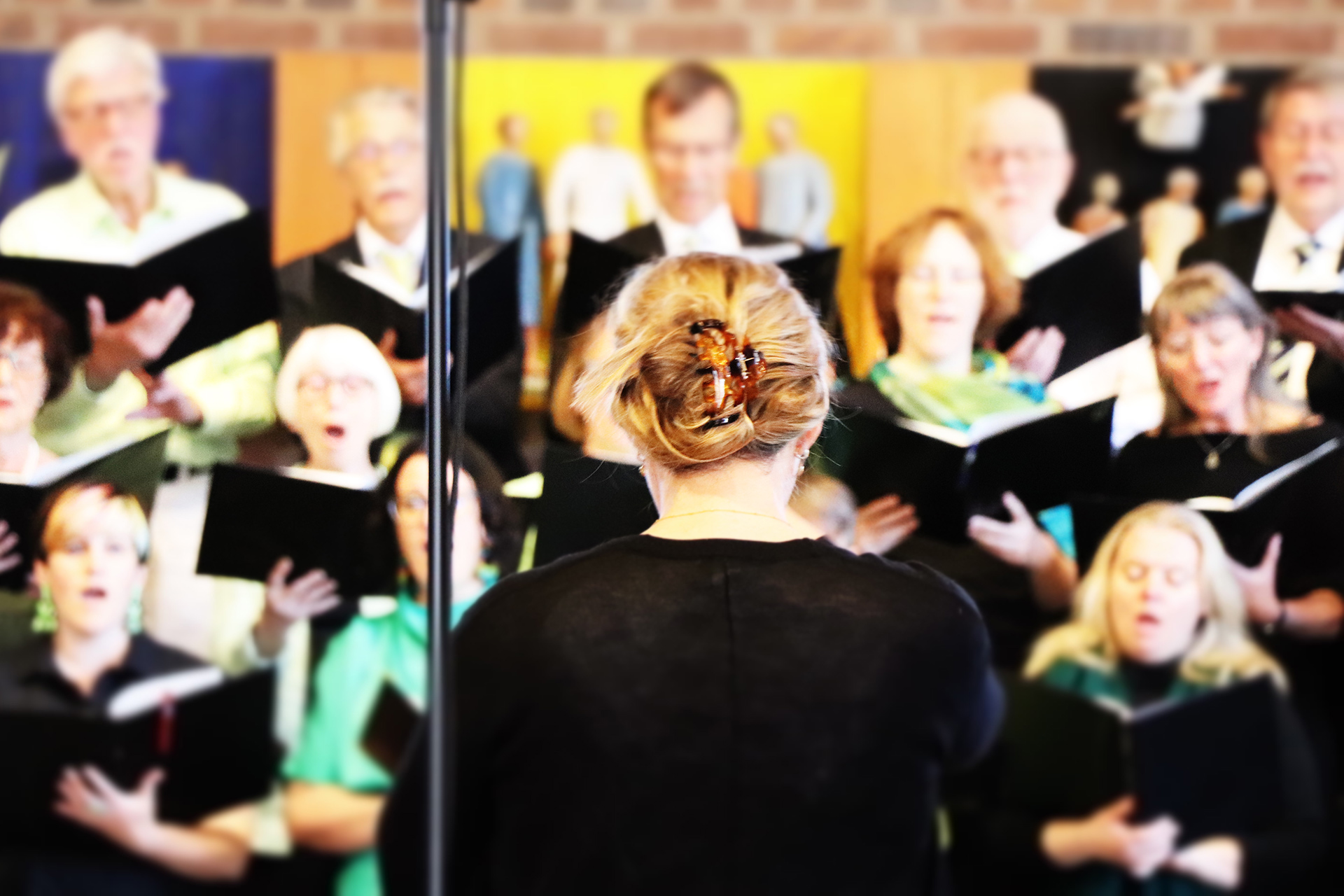 Ryggen av dirigenten, i bakgrunden körsångare. 