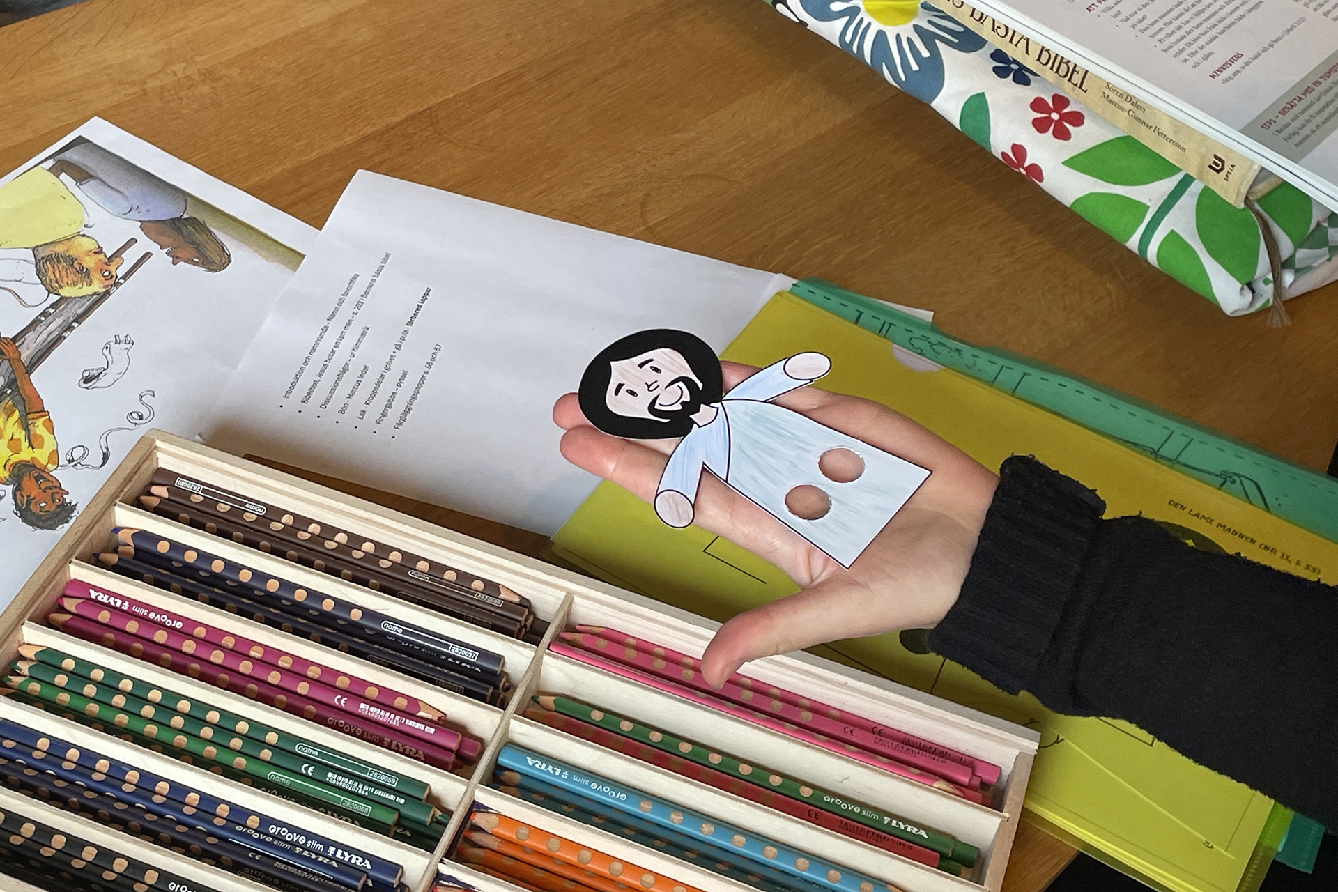 En hand håller en urklippt ritad person. 