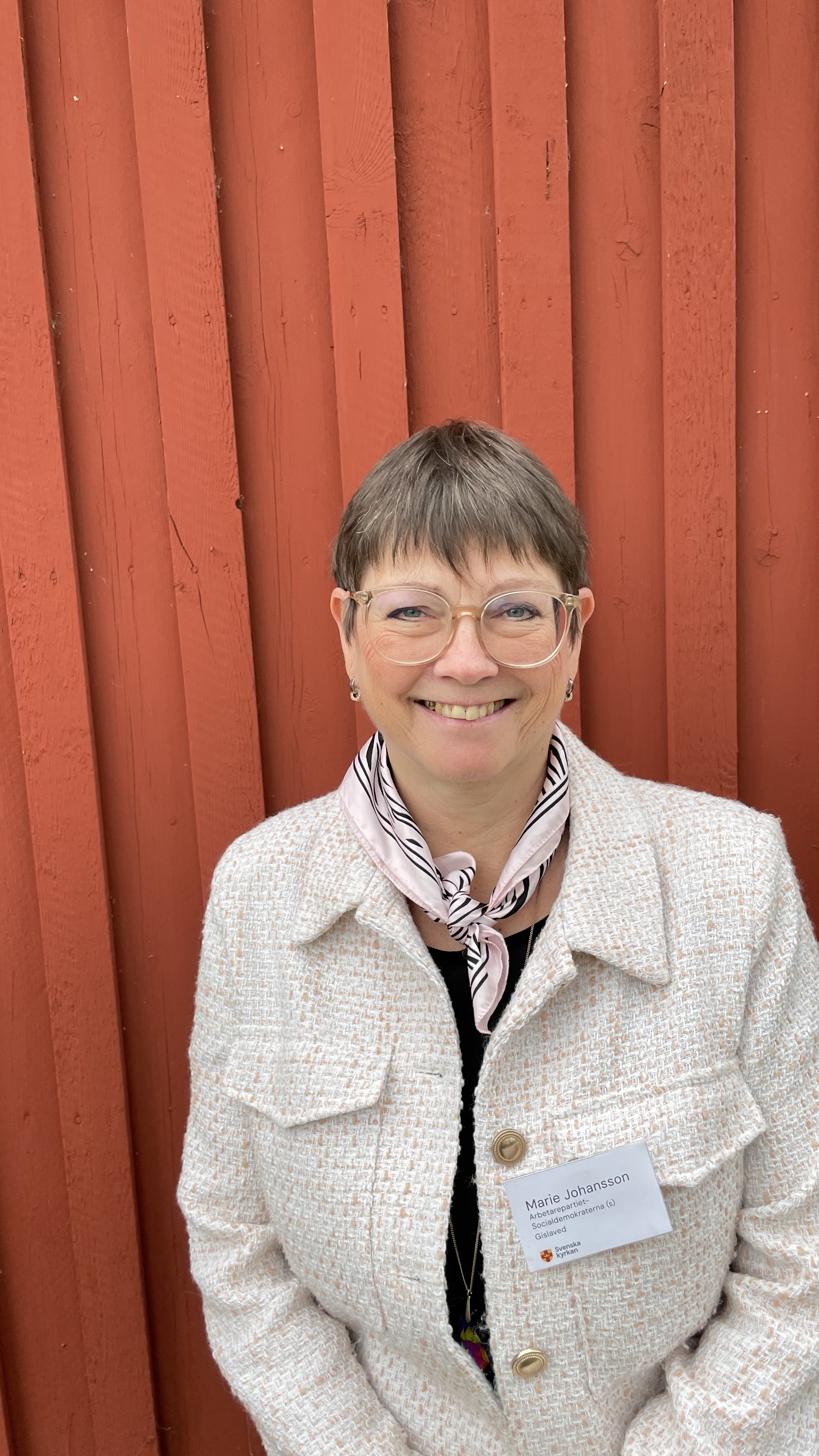 Porträttbild på Marie Johansson. Hon står med ryggen mot en faluröd byggnad.