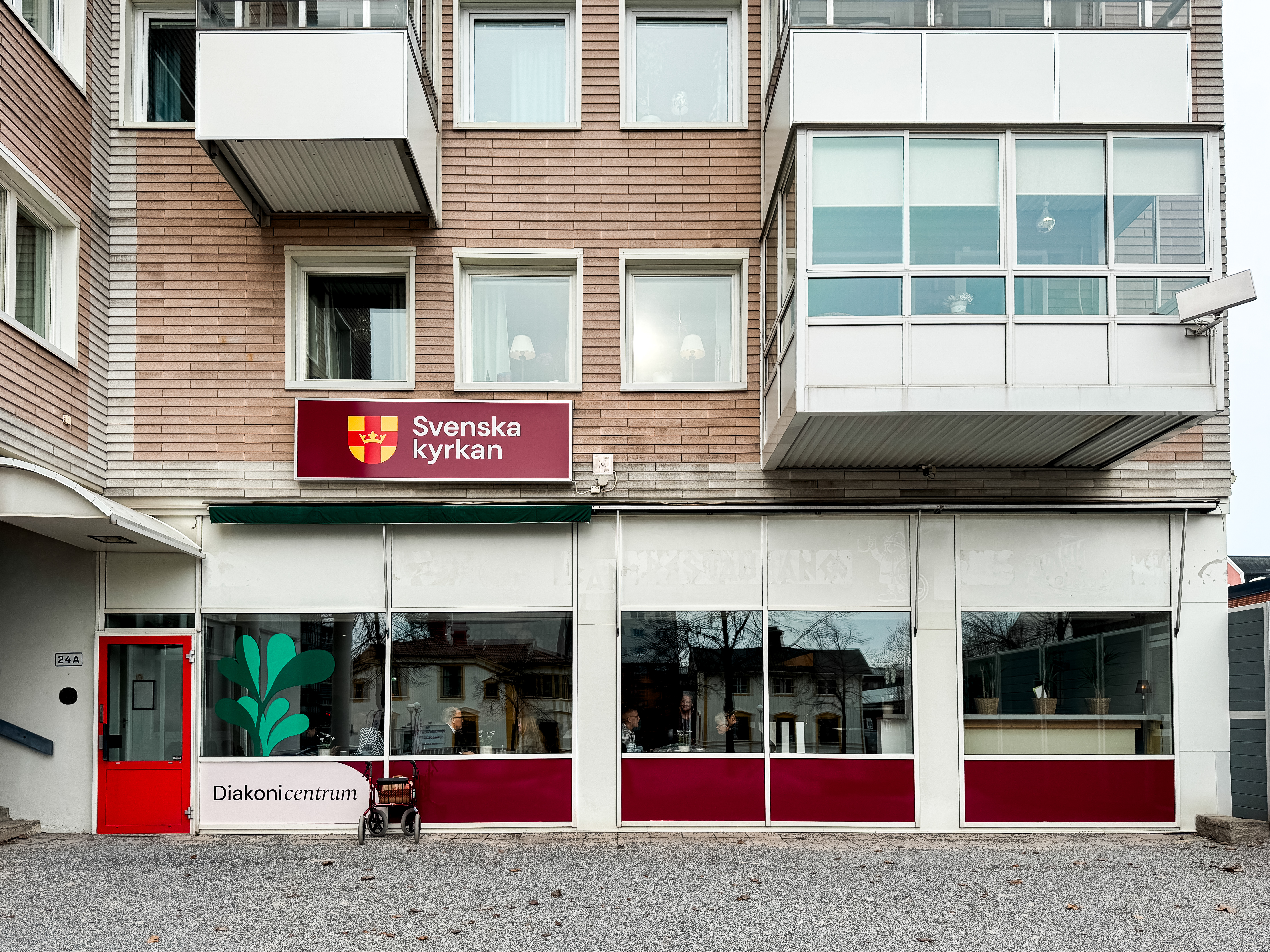 En byggnad med röd dörr och många stora fönster.