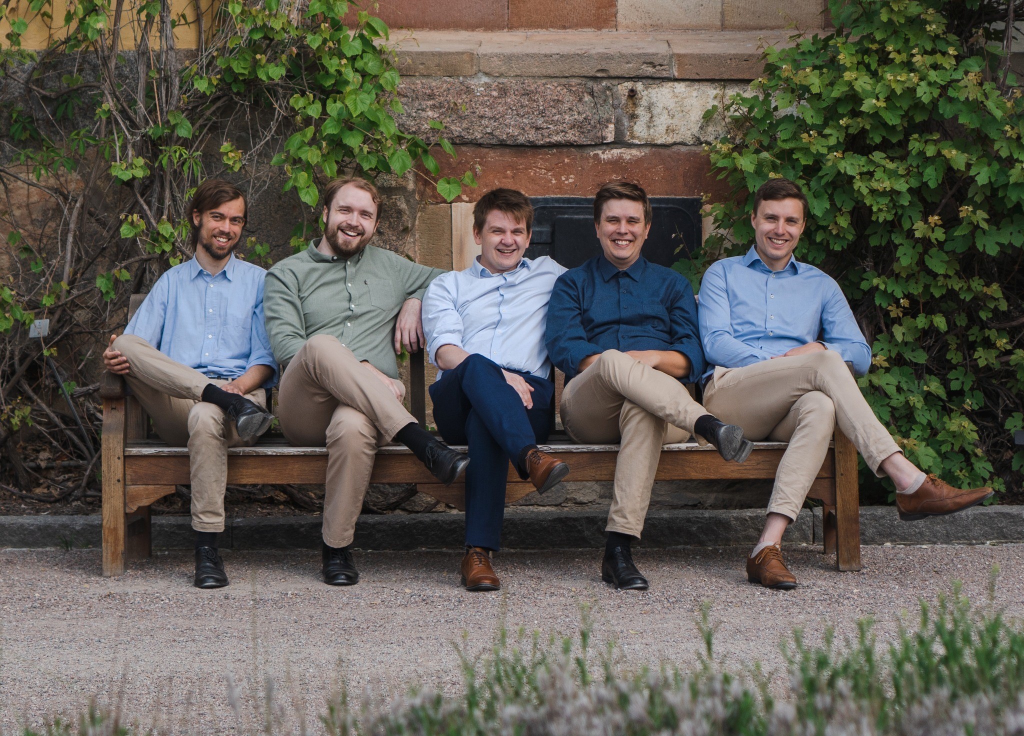 De fem sångarna i Simplyfive sitter uppradade på en bänk med benen över vänstra knäet, i chinos och skjortor i olika kulörer, och ler stort mot fotografen.