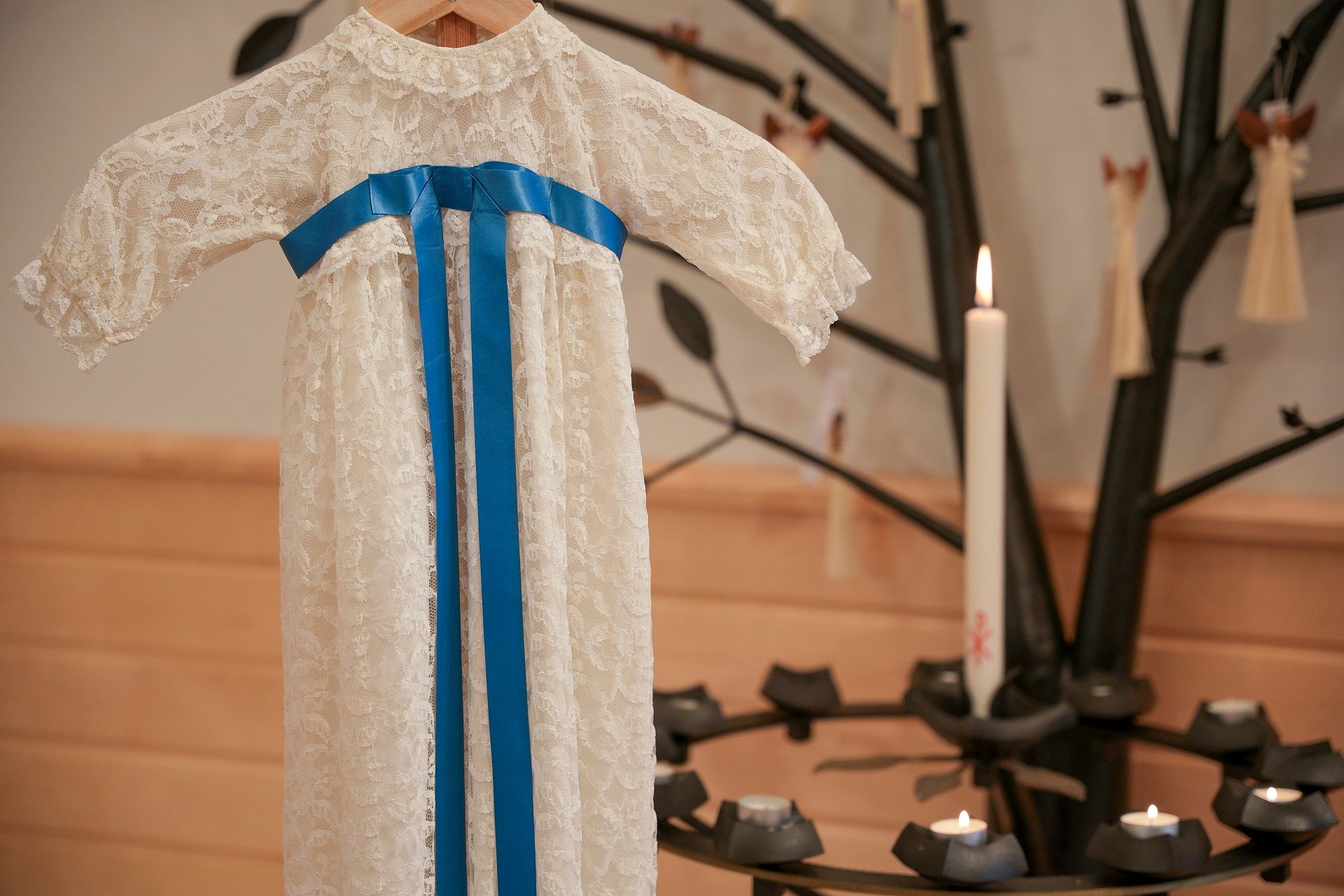 Dopklänning hänger i kyrkan vid en ljusbärare