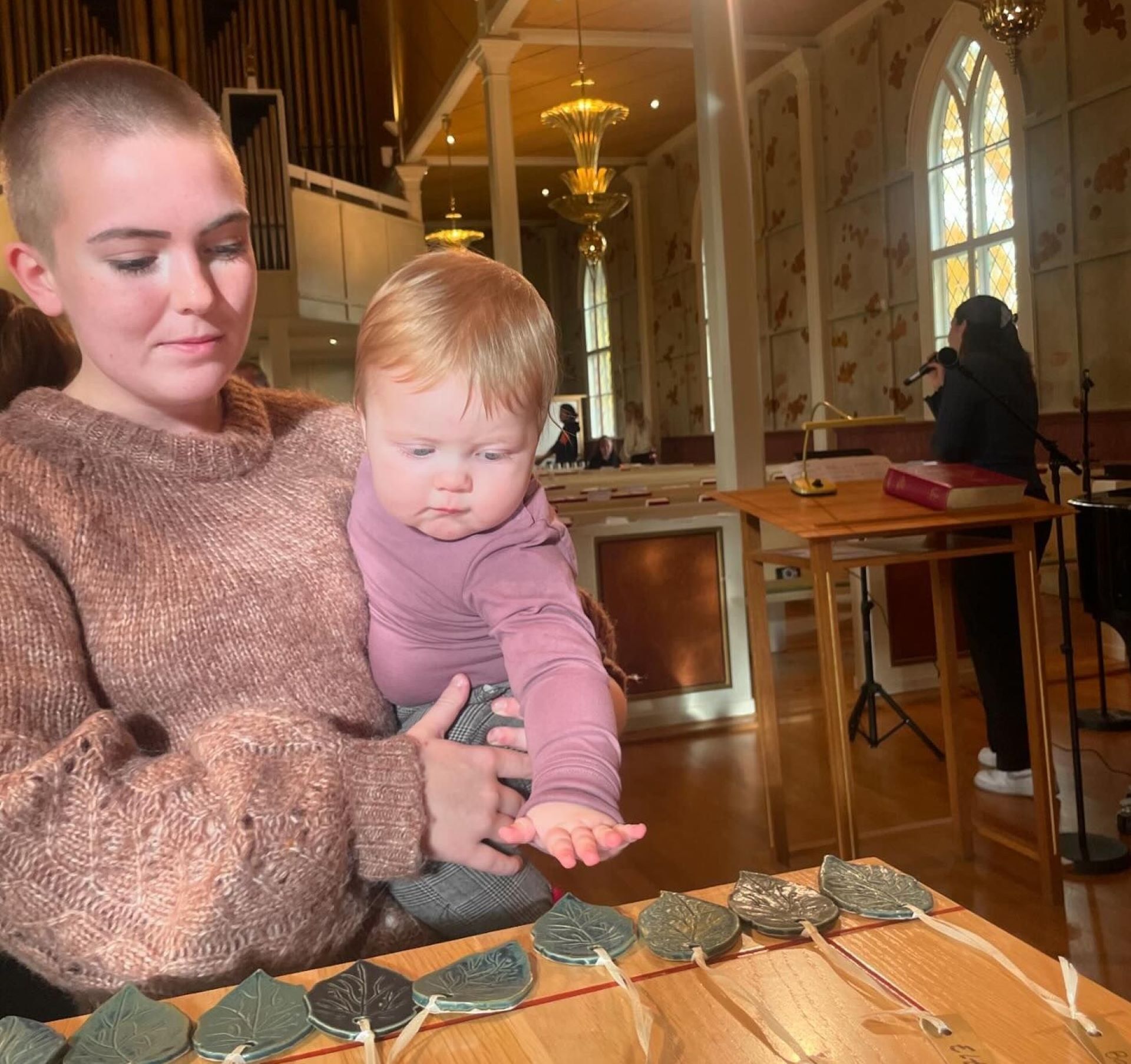 En mamma och sitt barn står framme vid altaret i kyrkan