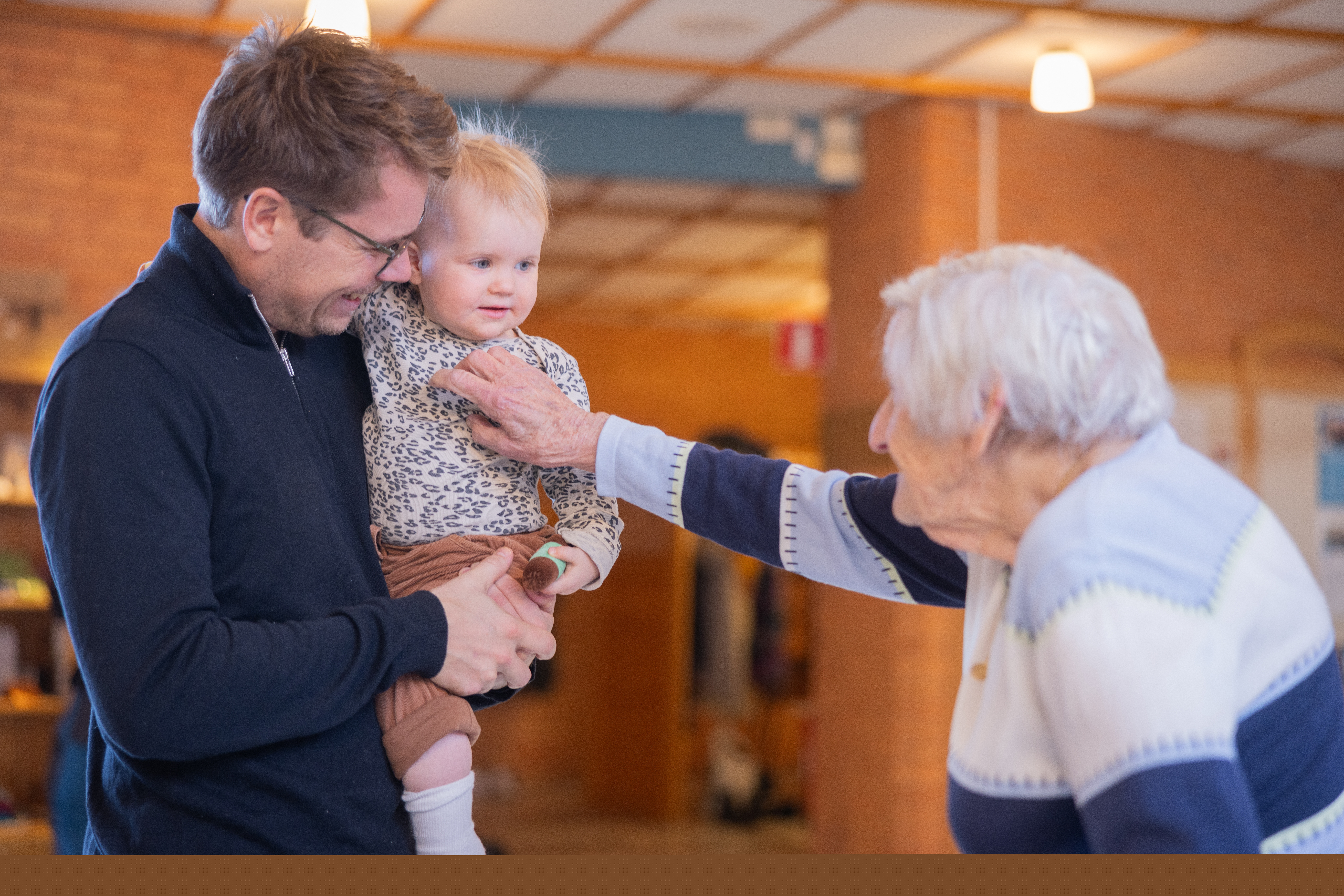 en pappa med ett barn som hälsar på äldre kvinna