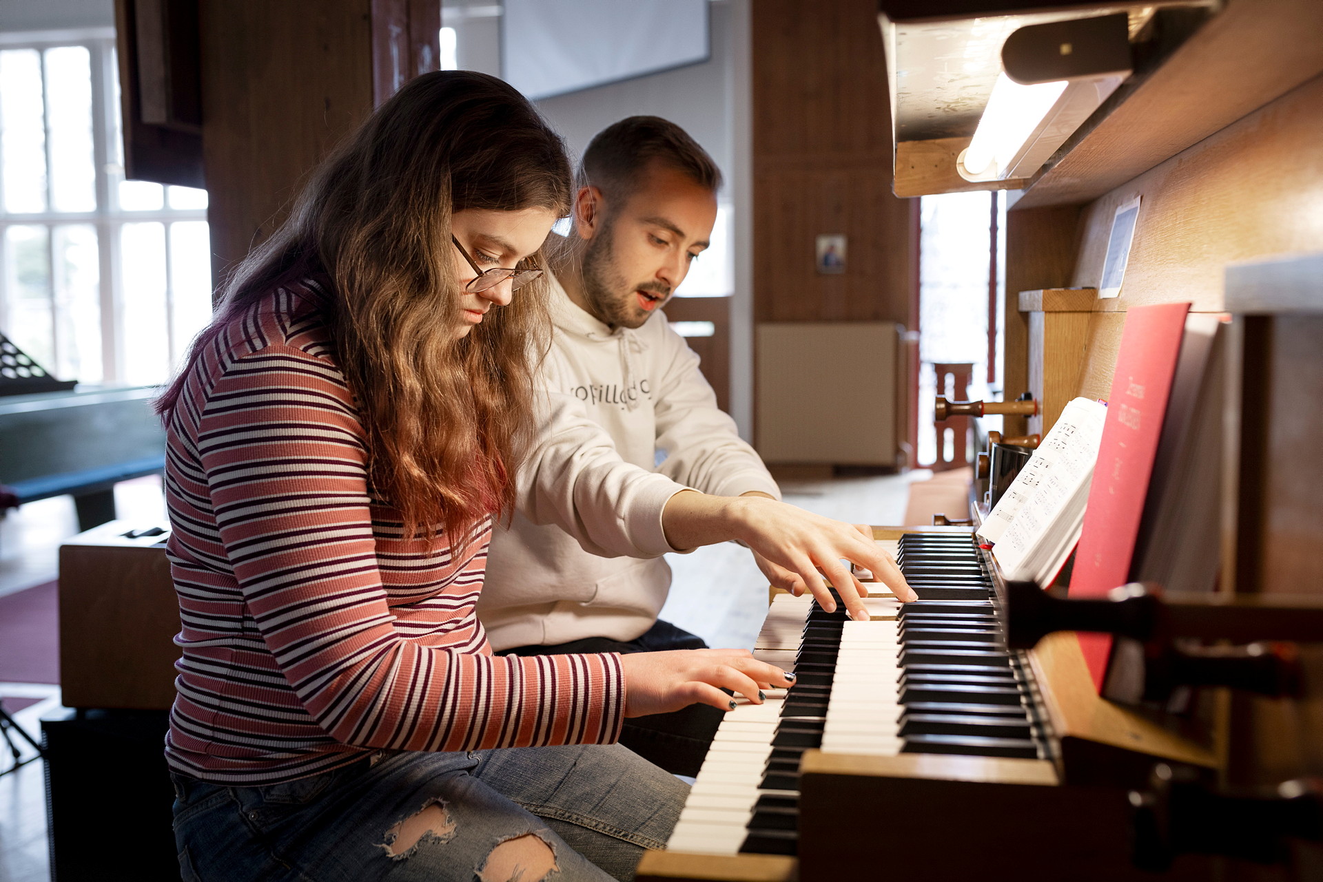 Två unga personer vid en orgel som spelar.