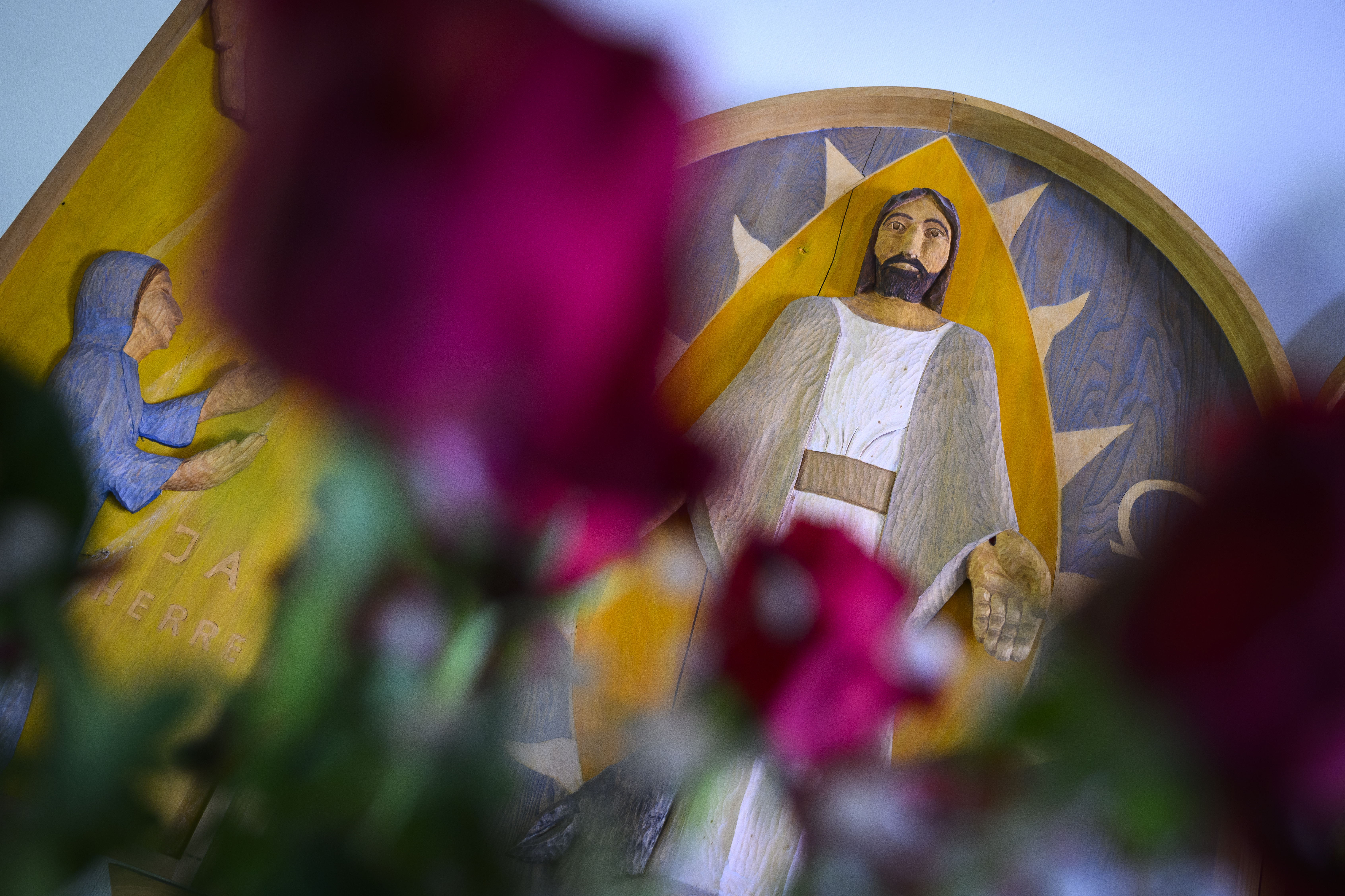 Bild på altartavla med avbild på Jesus med blommor i förgrunden.