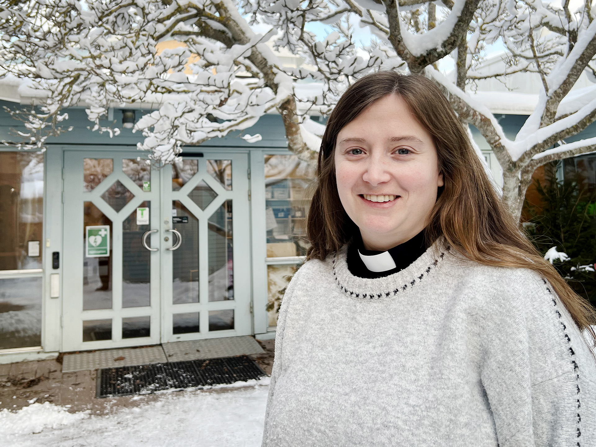 kvinna framför träd och dörr, snö på marken