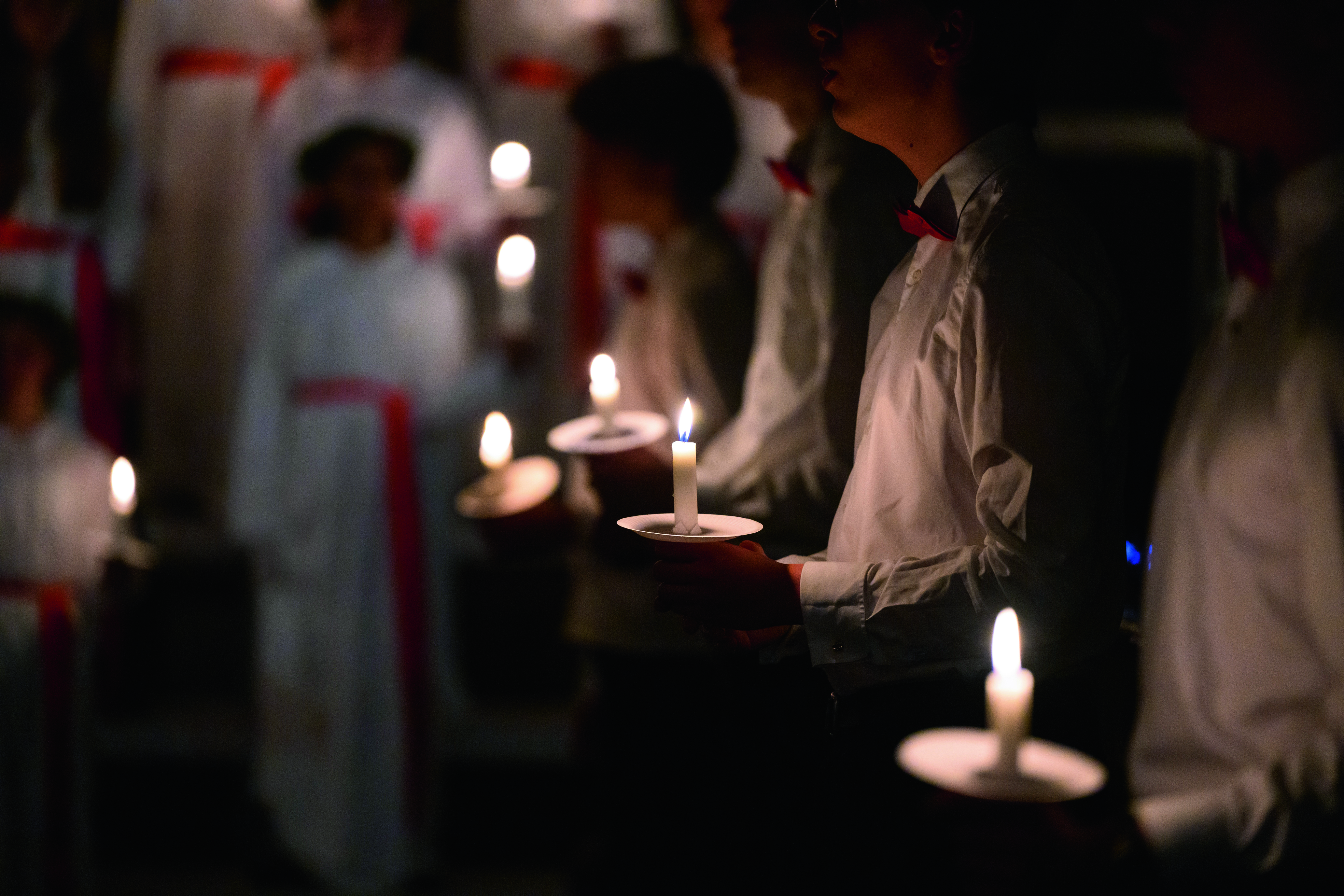 barnhänder som håller ljus i ett luciatåg