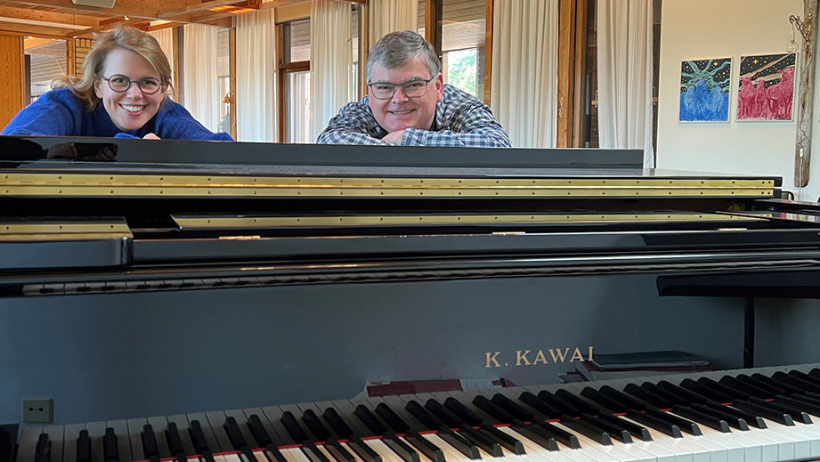 Närbild på flygel med församlingens två organister vid sidan