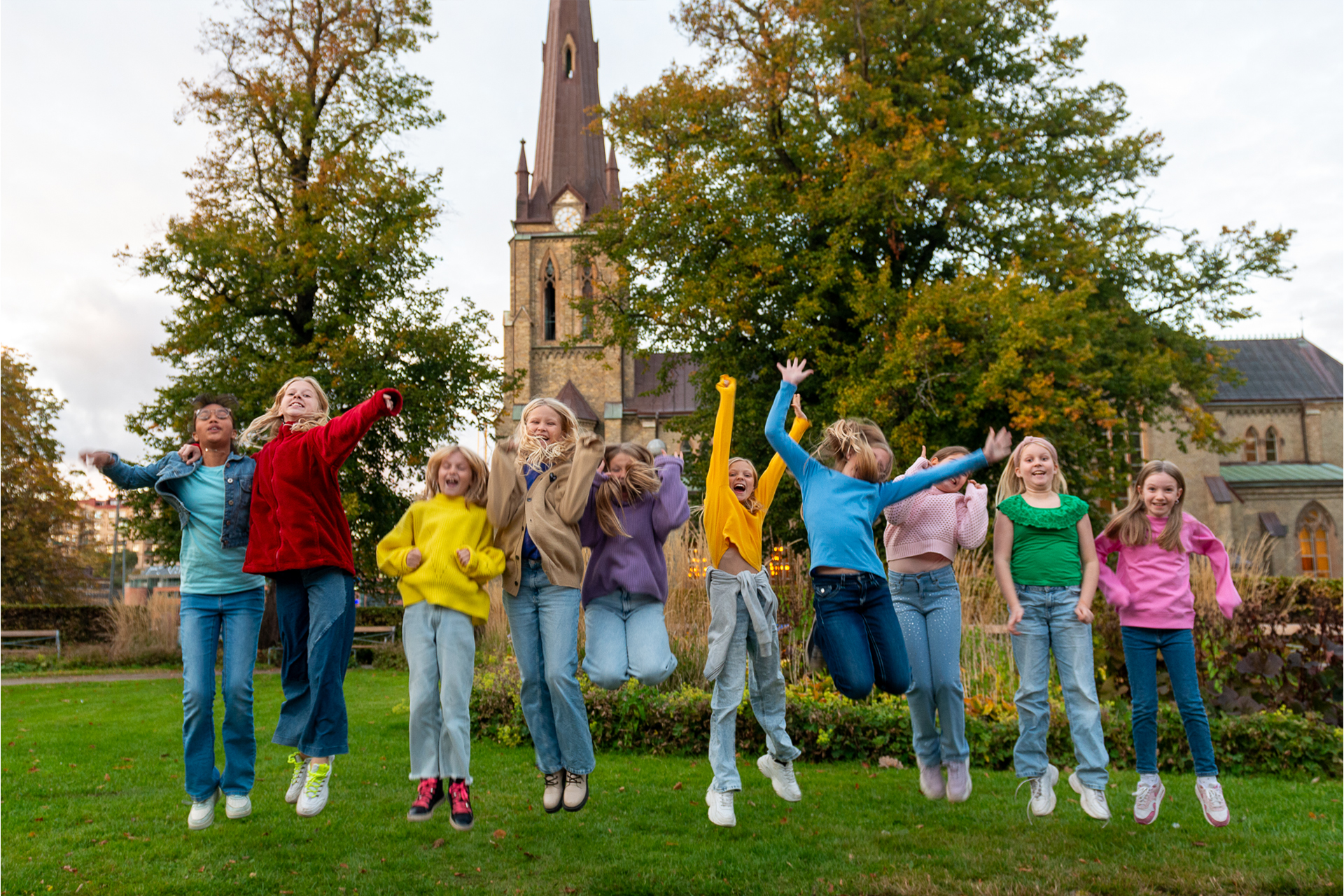 Barn hoppar i gräset utanför Hagakyrkan i Göteborg.