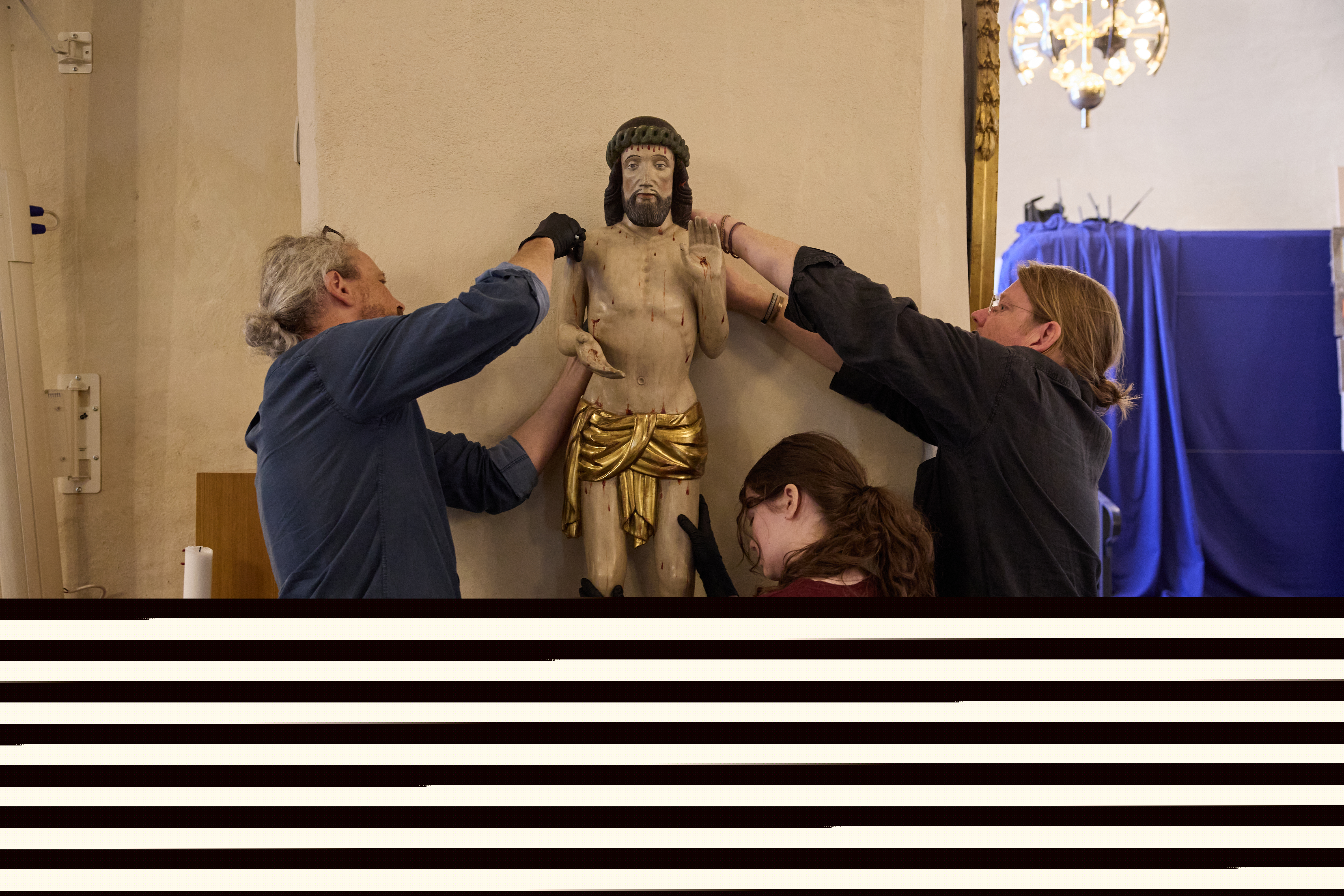 Tree personer håller i Jesus som träskulptur