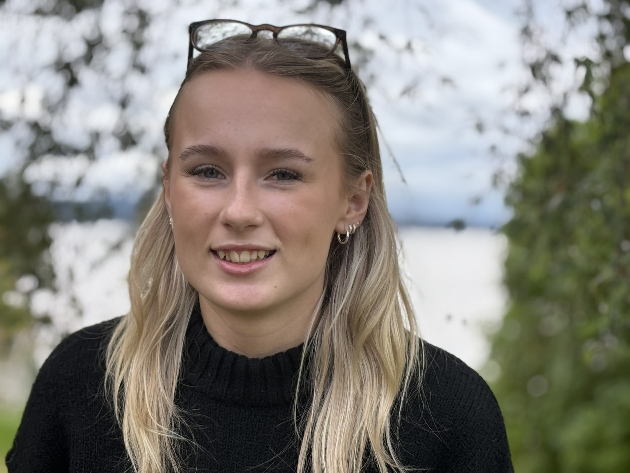 Kvinna med blont hår fotograferad framifrån med sjön Siljan i bakgrunden,