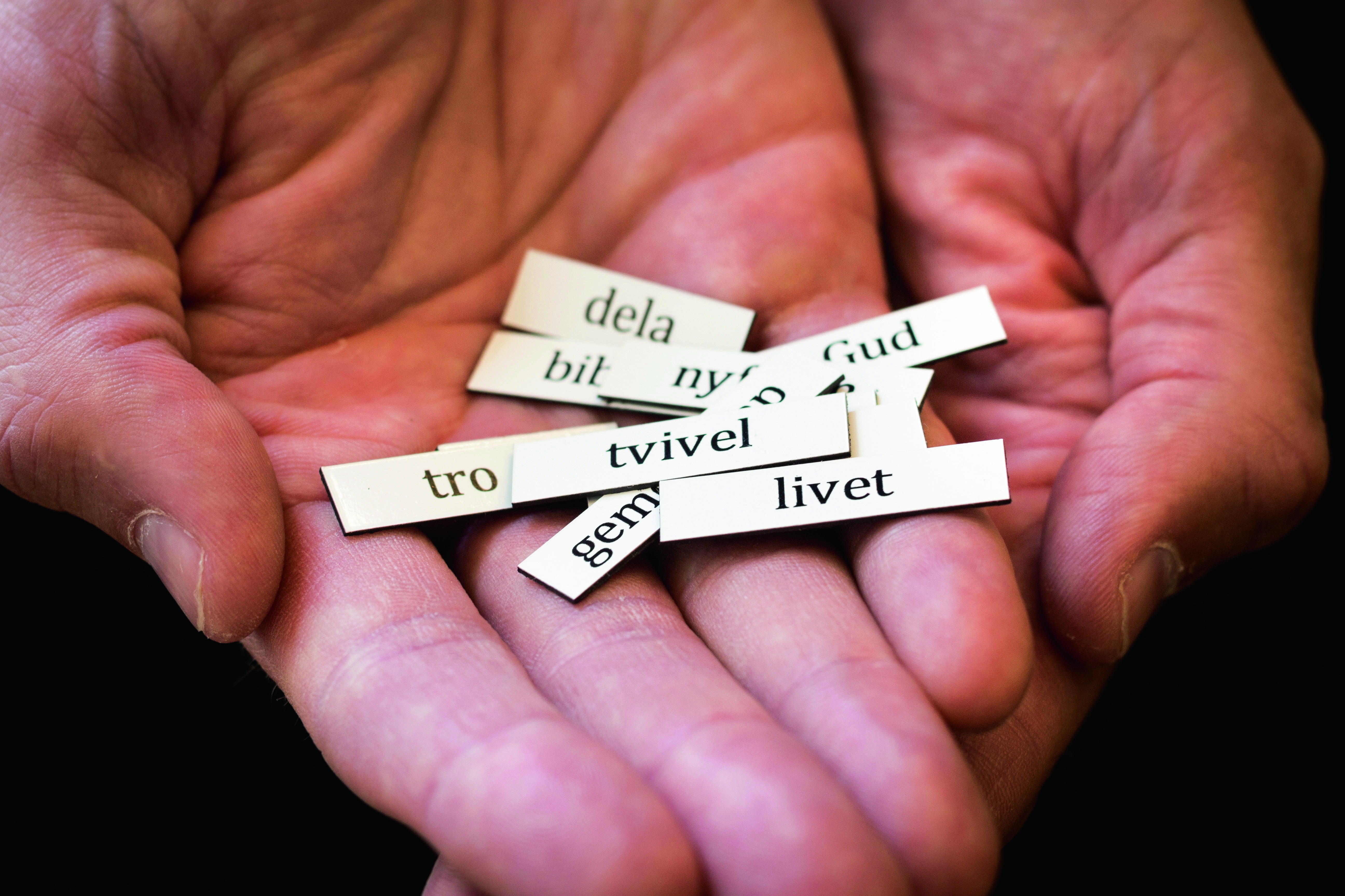 Tbå öppna händer med ordlappar som det står "tro", "tvivel", "livet" på.