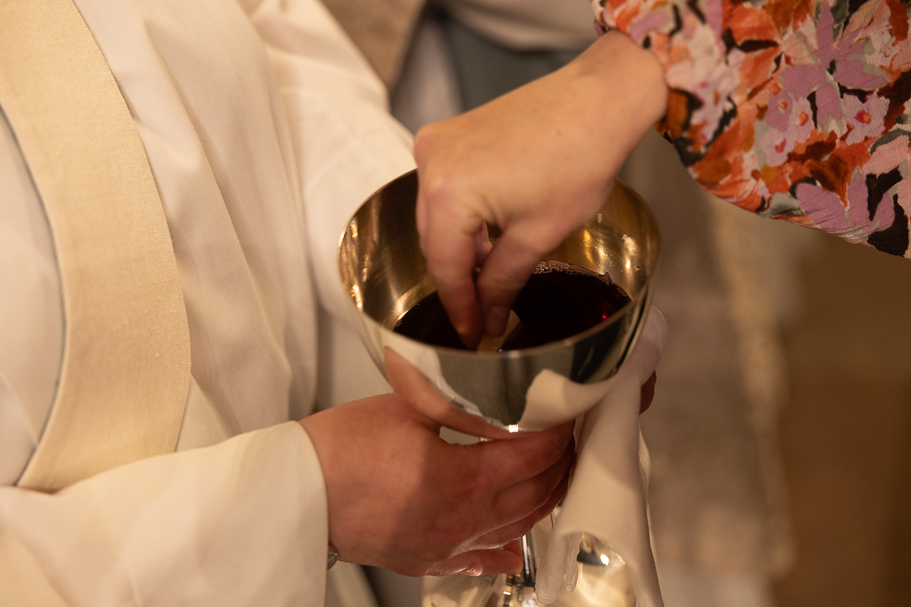 Hand som doppar nattvardsbröd i skål med vin.