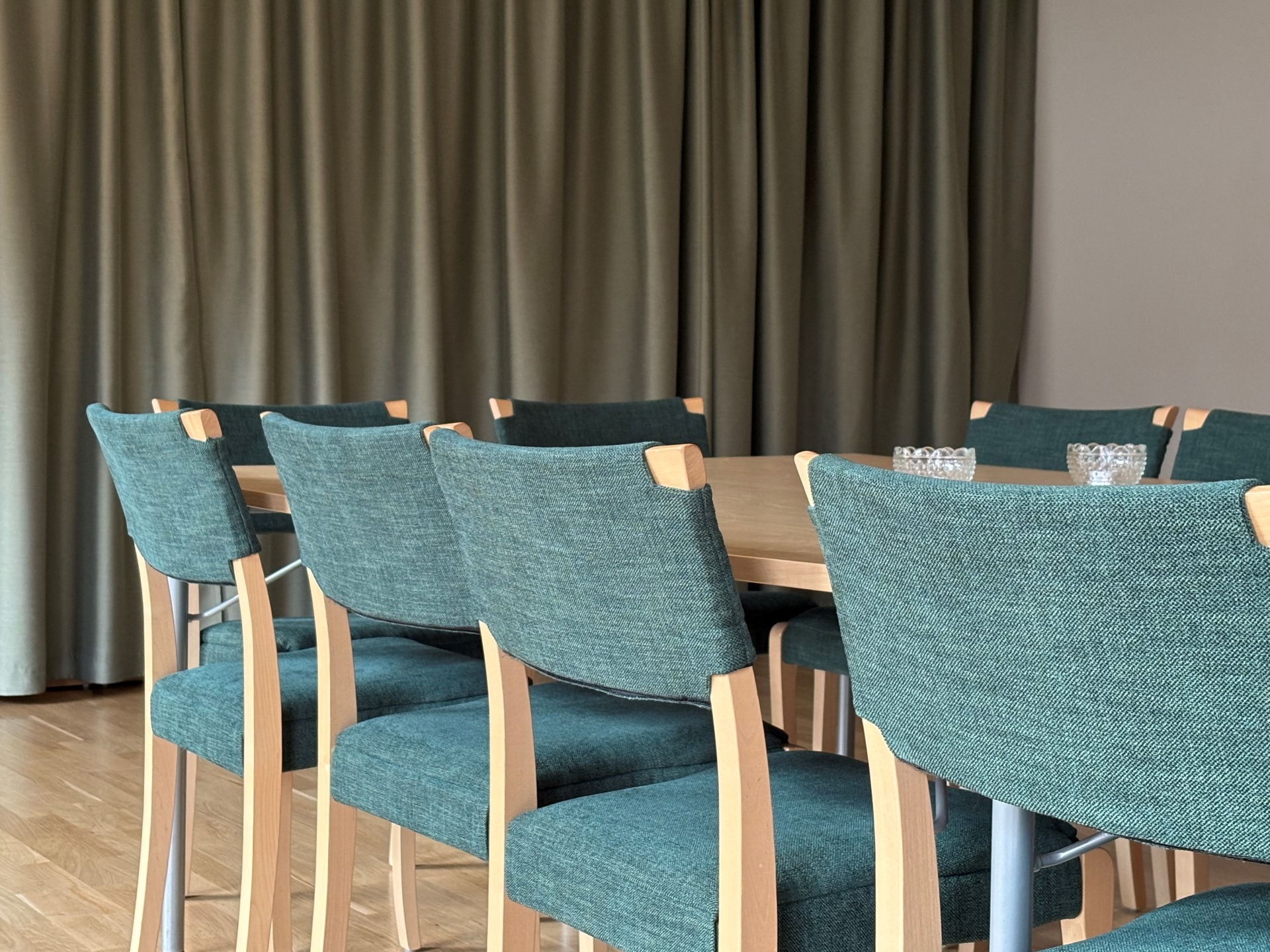 Nyrestaurerade klädda konferensstolar runt ett mötesbord.