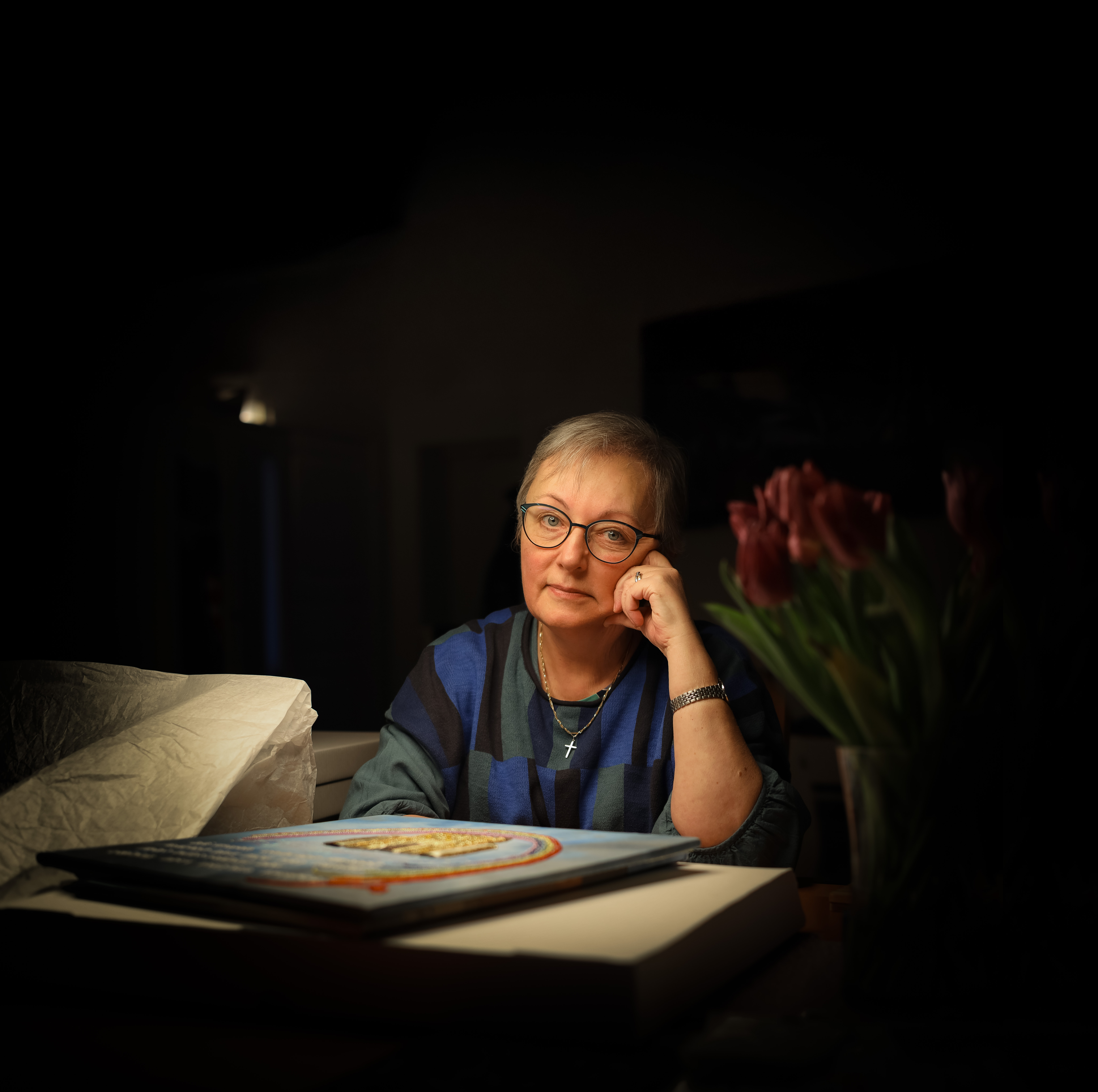 Erika Cyrillus sitter och tittar in i kameran med en av sina broderade bilder framför sig.