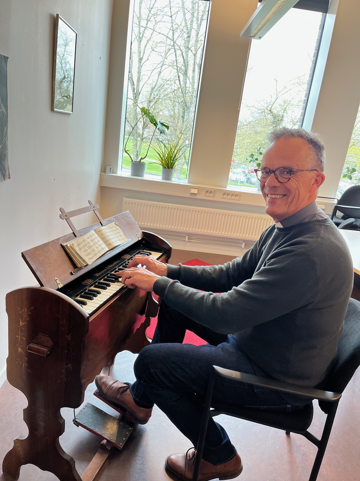 Carl Sjögren sitter vid en gammal tramporgel och spelar. 