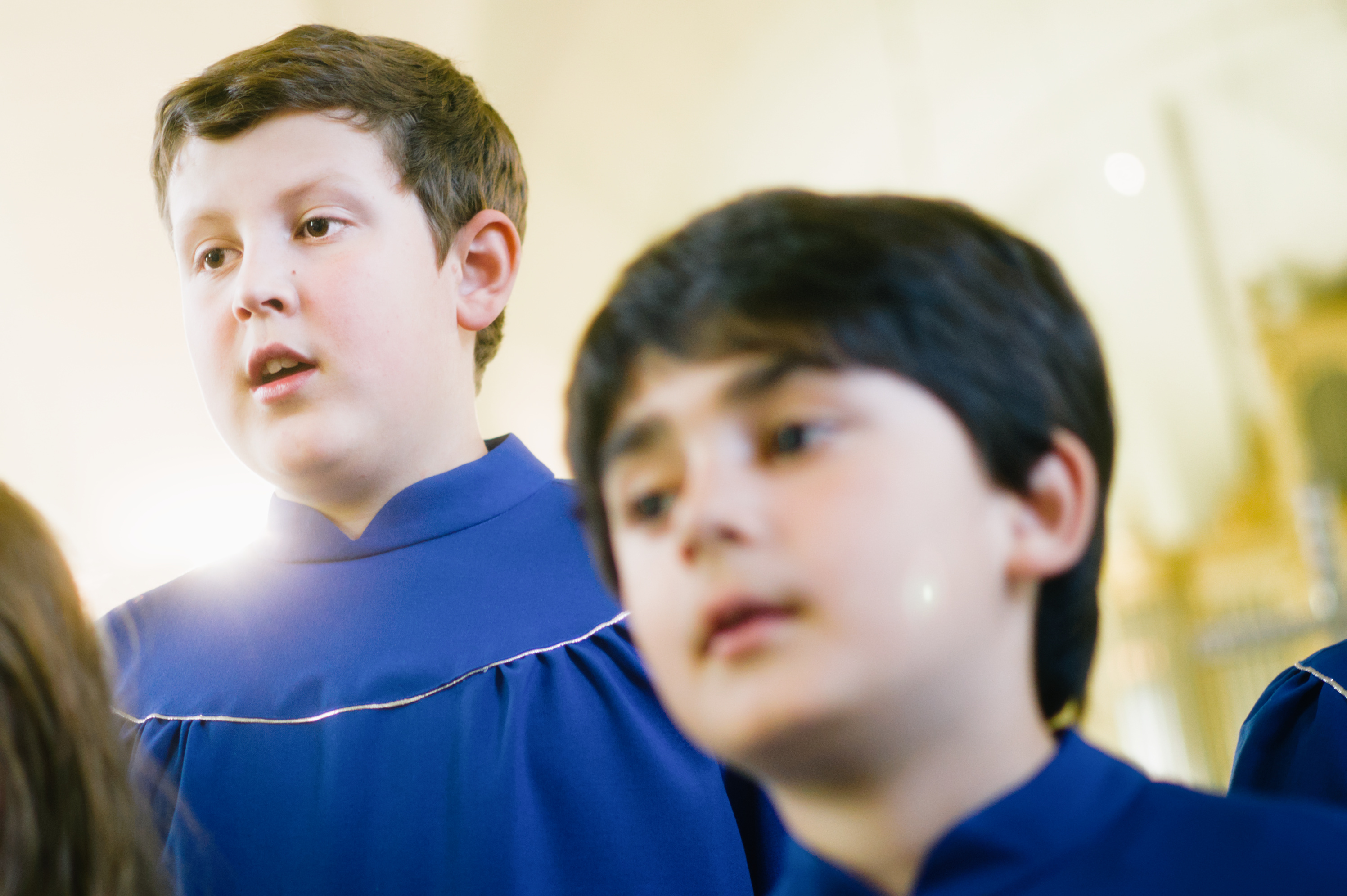 Närbild på två pojkar i två kåpor som sjunger i kyrka