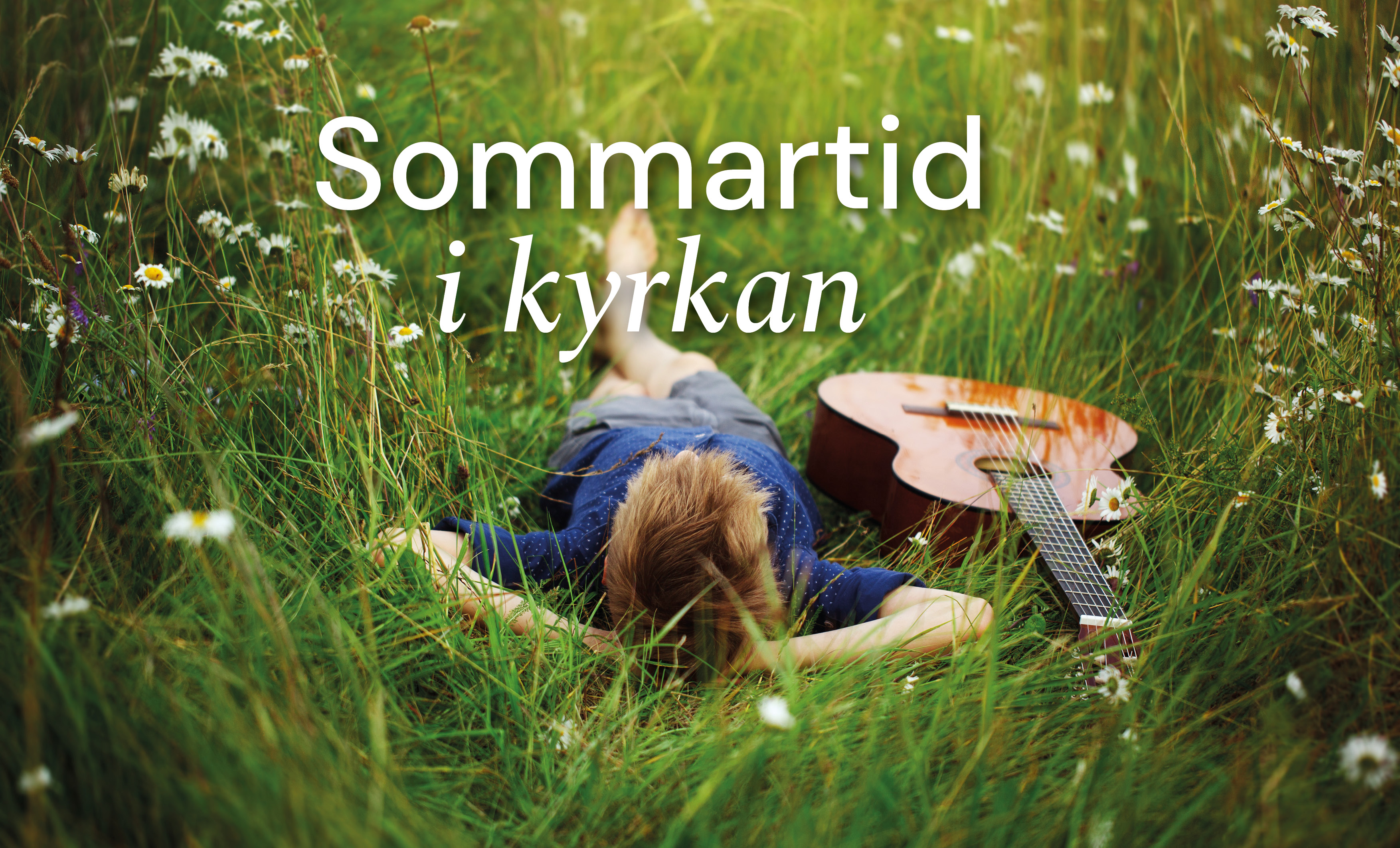 En ung kille ligger i högt gräs med huvudet mot kameran. Han ligger på rygg med händerna under huvudet och ser avslappnad ut. Bredvid honom ligger en gitarr.