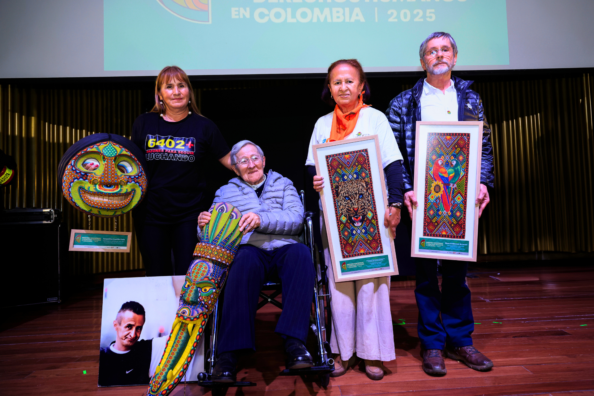 Fyra personer, tre kvinnor och en man, på scen med priser föreställande colombianska konstverk