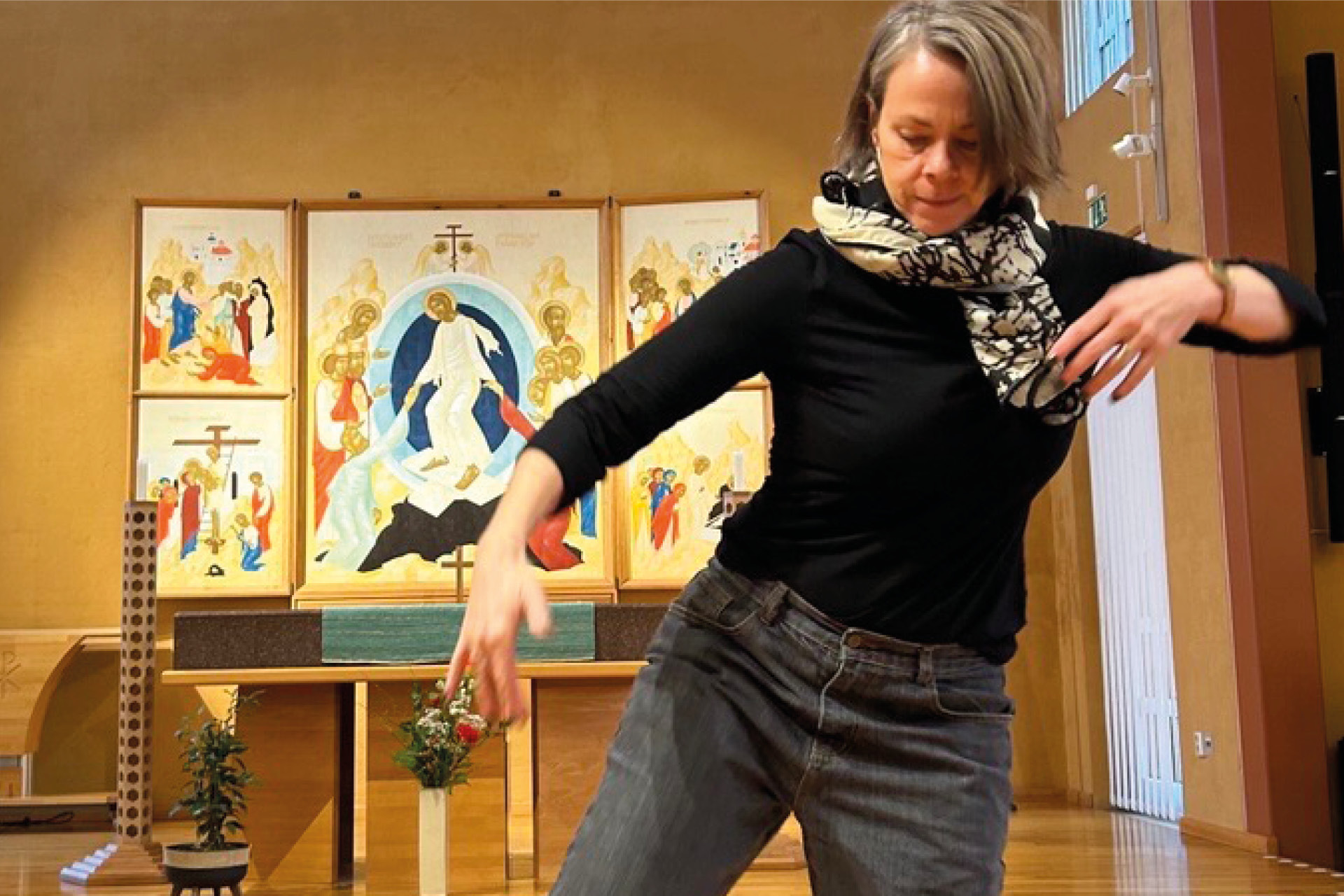 Kvinna i rörelse i ett danssteg i en kyrka med altare och altartavla i bakgrunden.