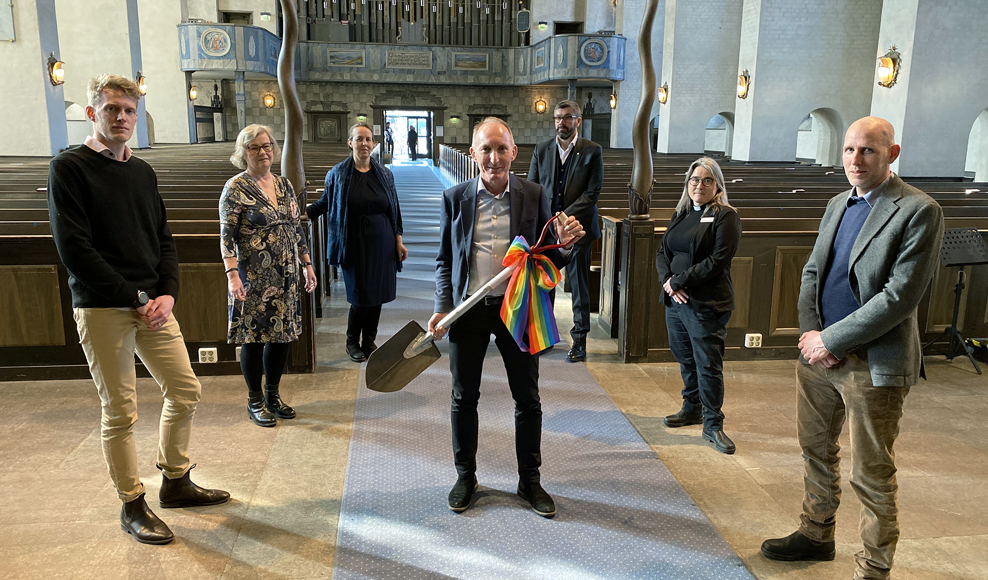 Ett antal personer står samlade i Högalidskyrkan. Den som står längst fram håller en spade i handen. 