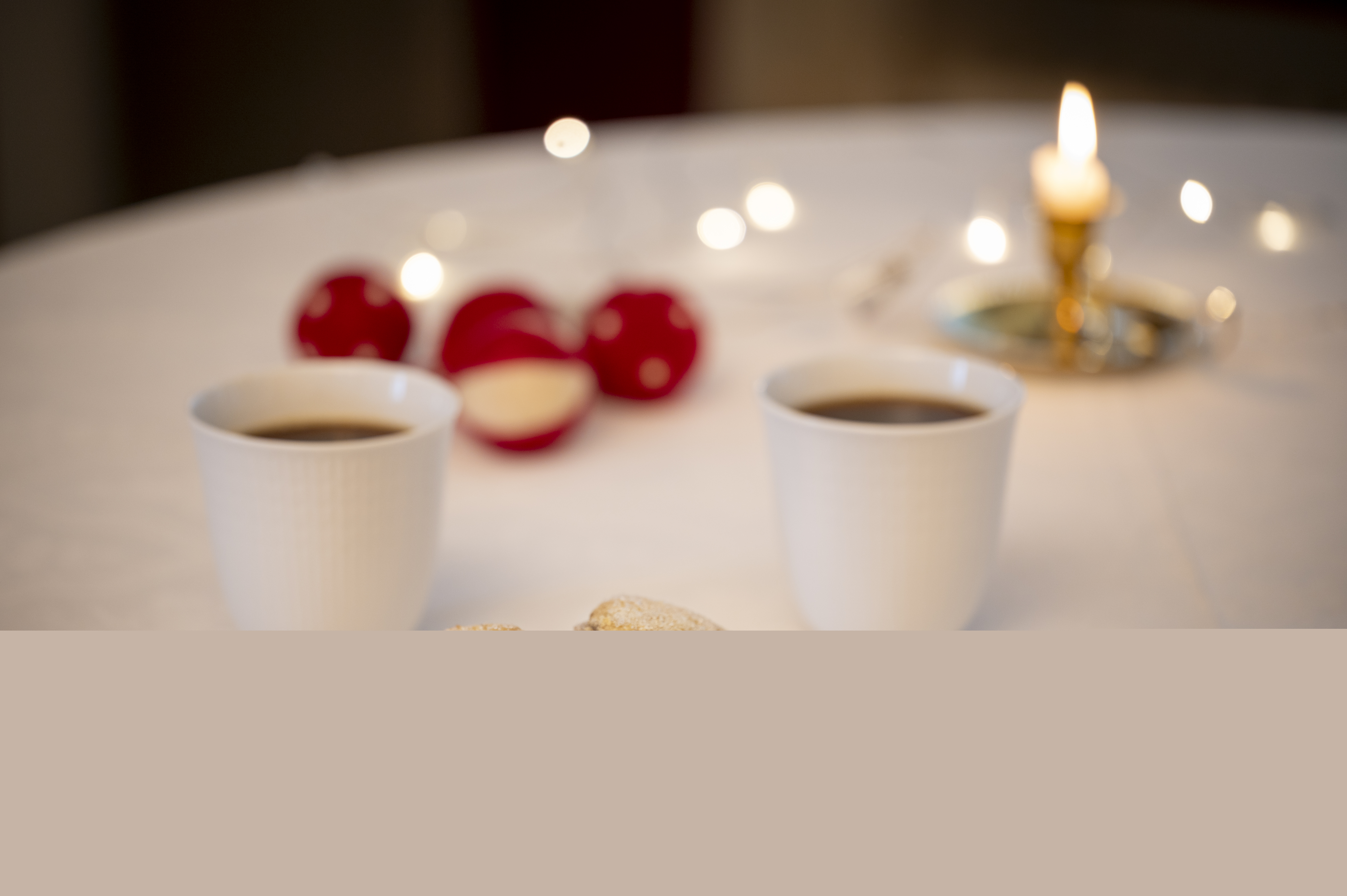 Småkakor, kaffe och ljus på bord med vit duk