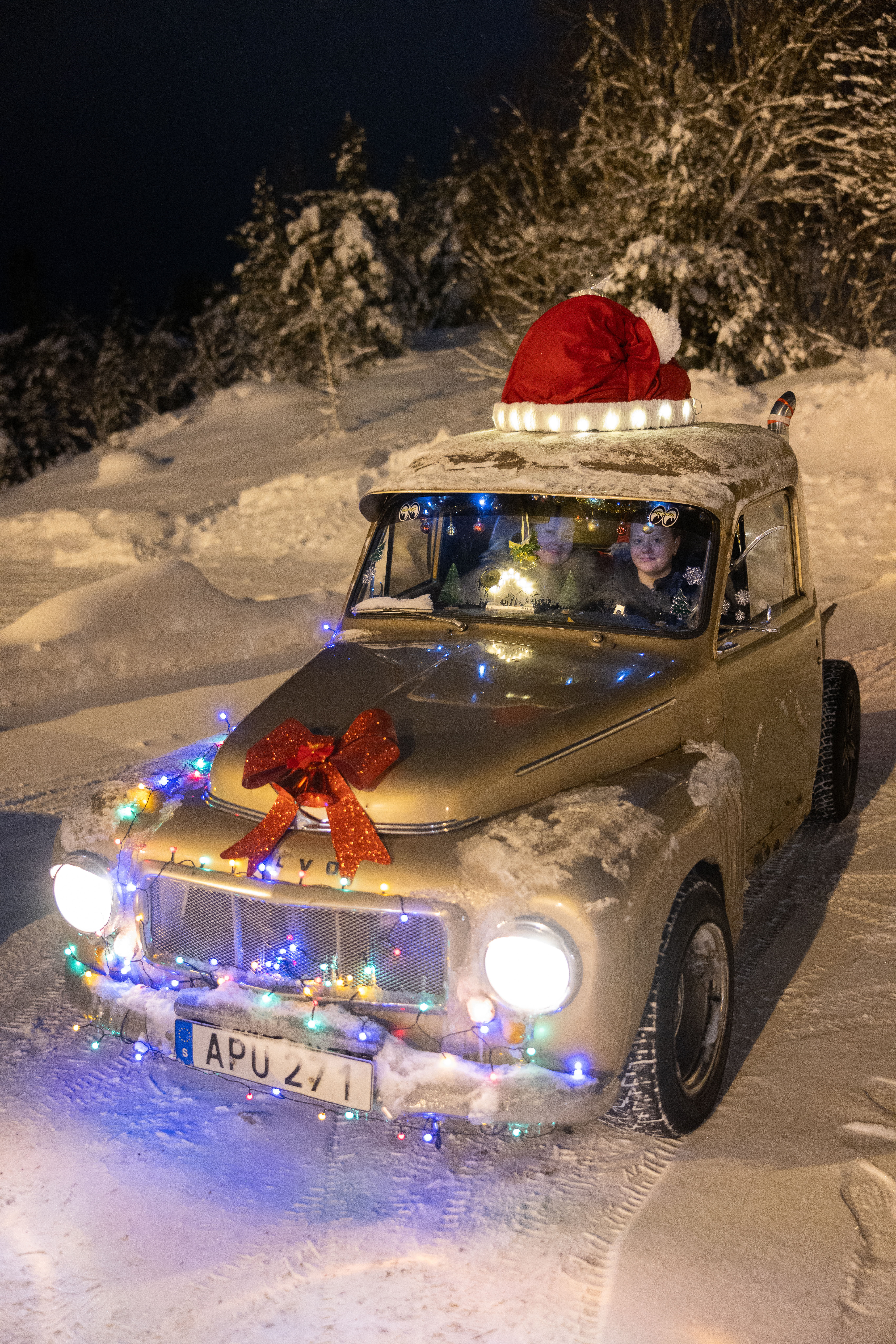 Epa bil kör på snö utsmyckad med julmössa och ljus