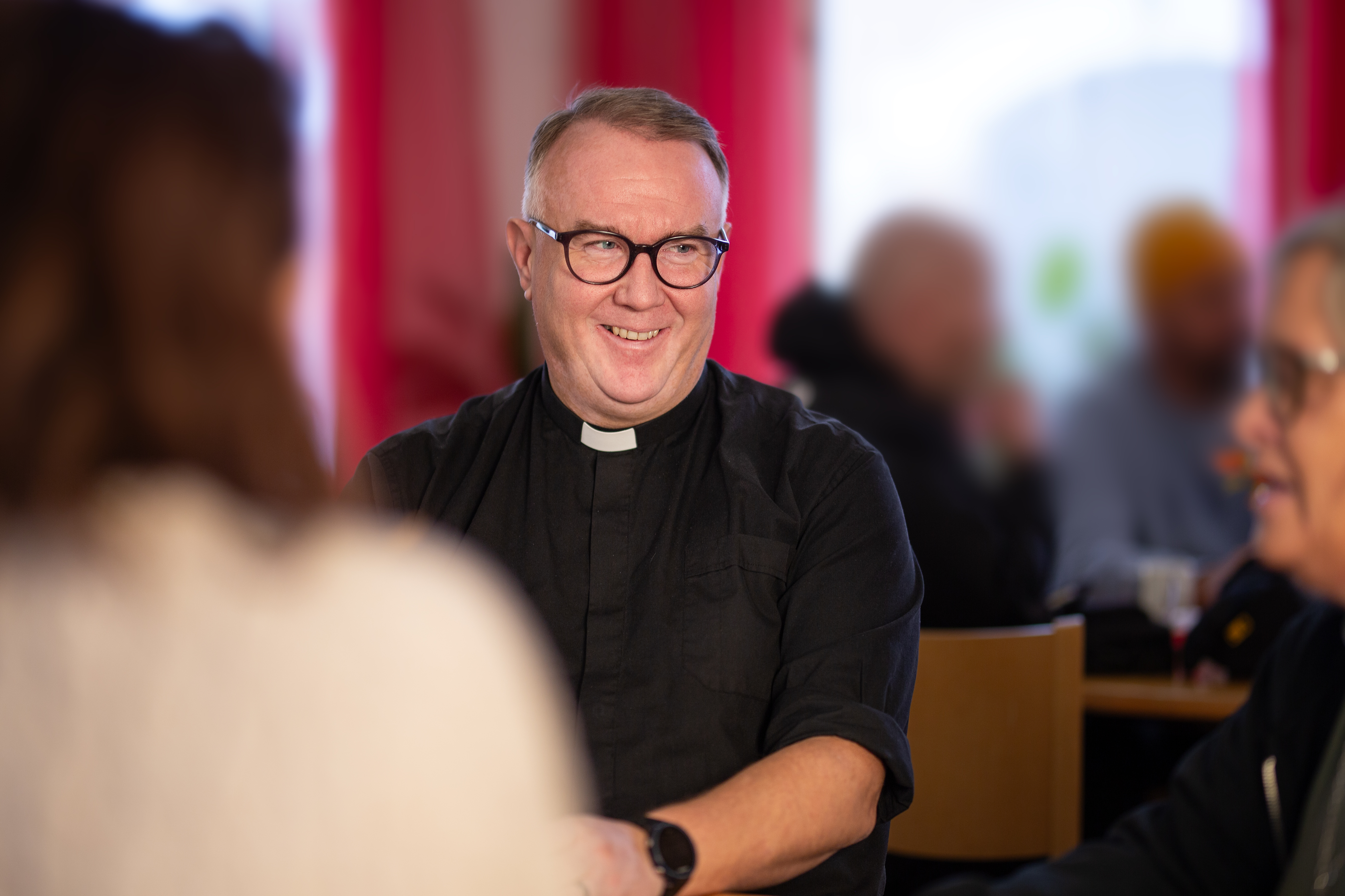 Domprost ler, sitter inomhus på DIC tillsammans med personal