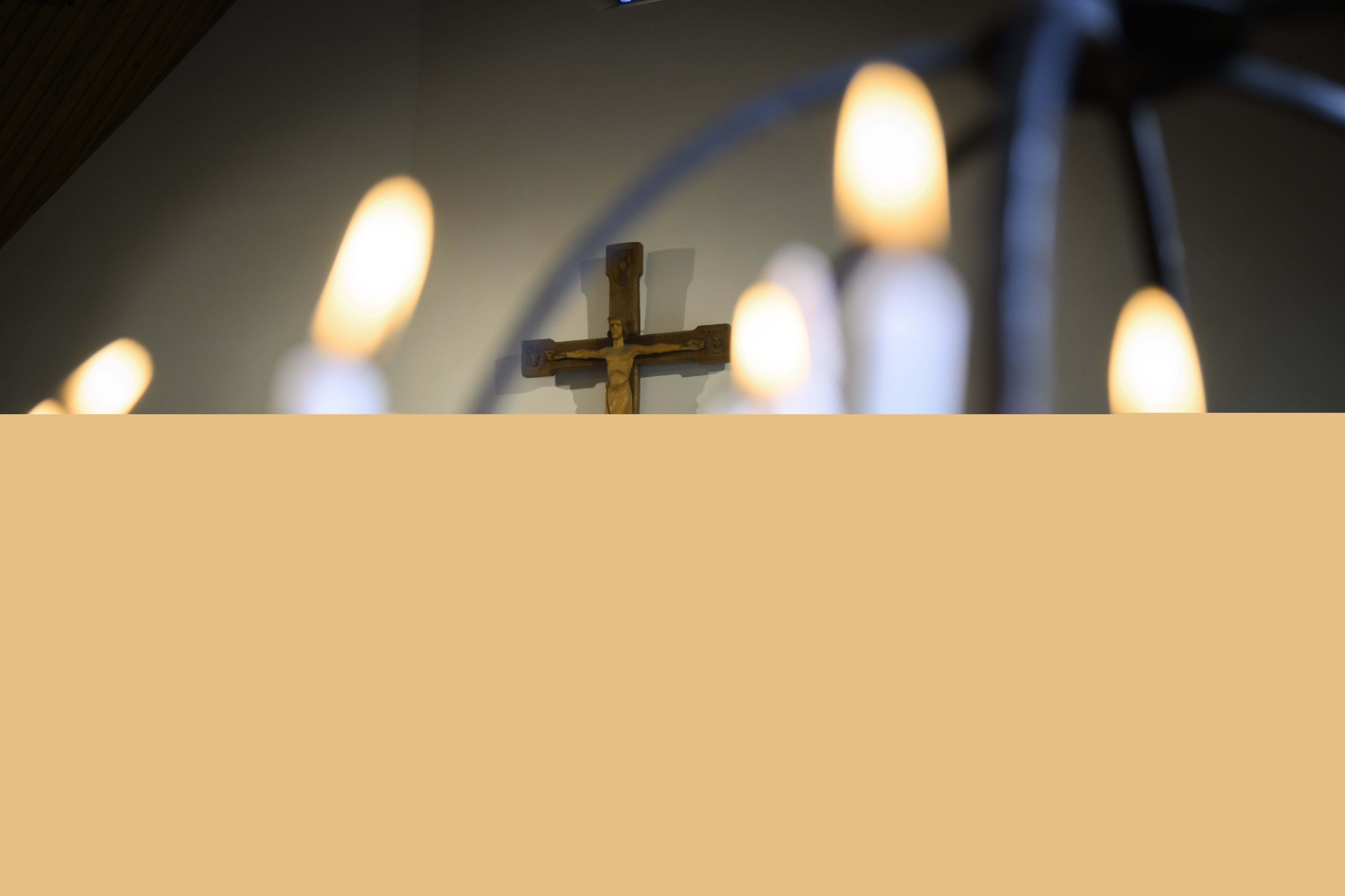 Tända stearinljus med kors i bakgrunden i en kyrka.