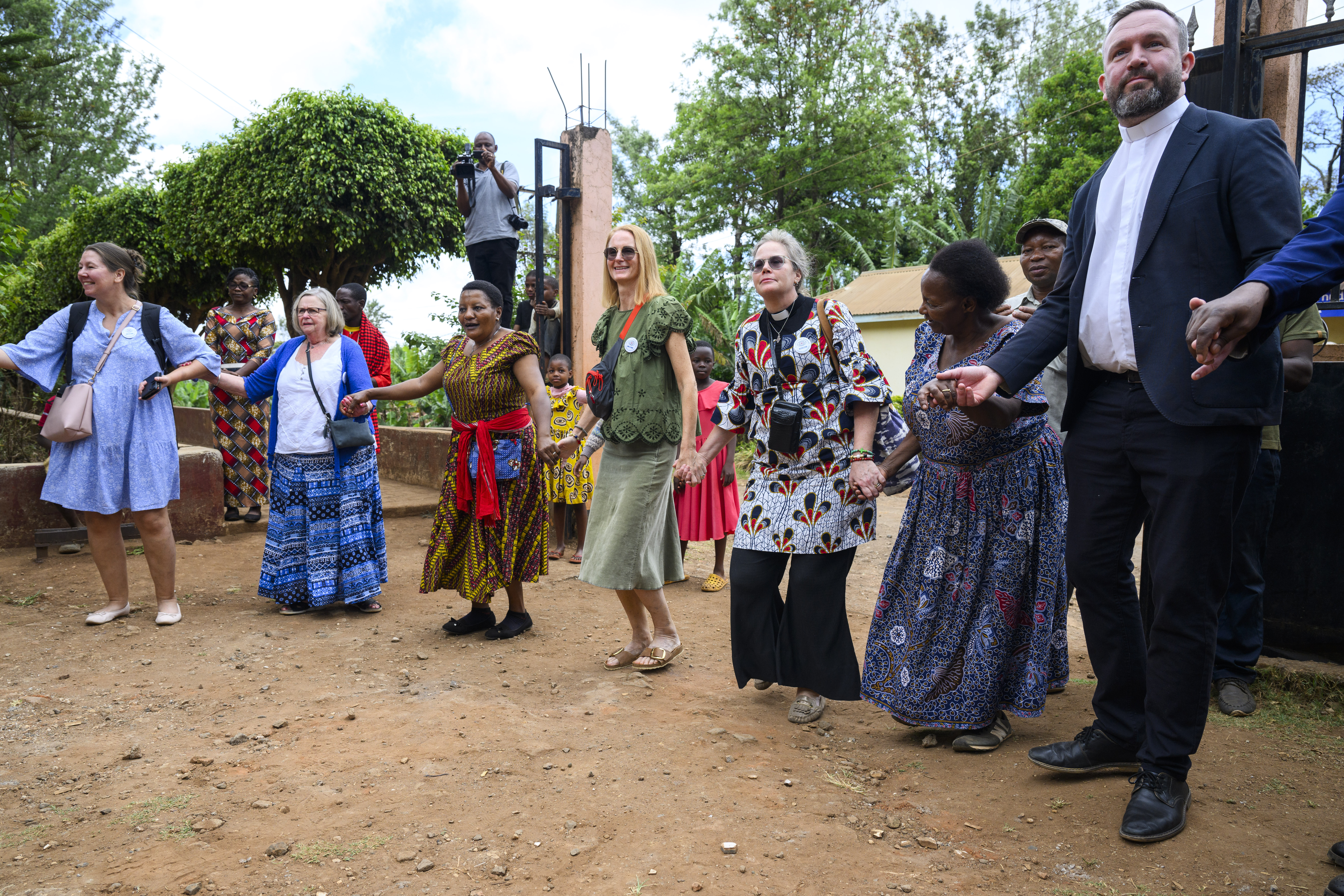 En rad personer där alla håller varandra i hand. De ler och skrattar.