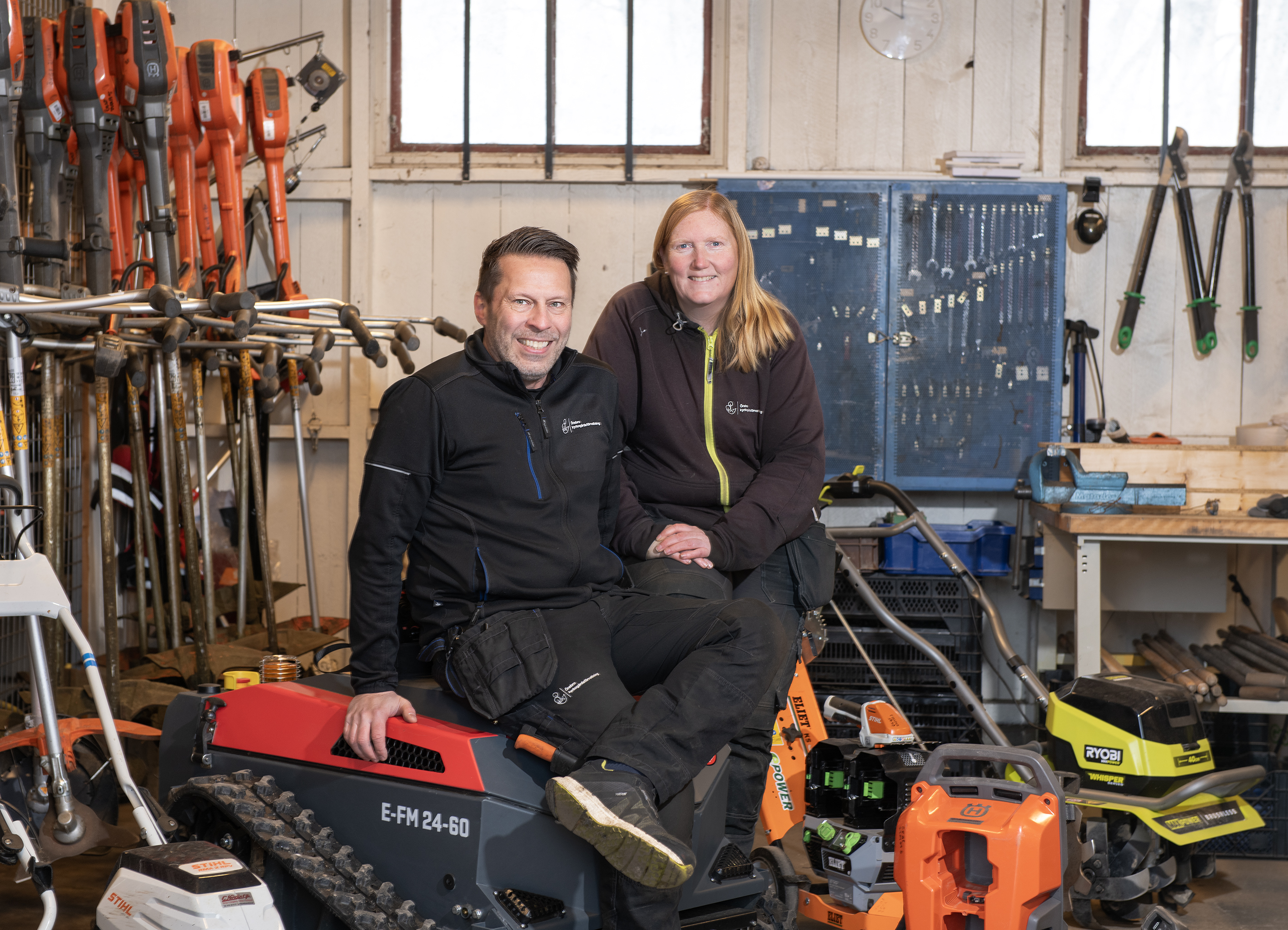 Man och kvinna i en verkstad med många maskiner.