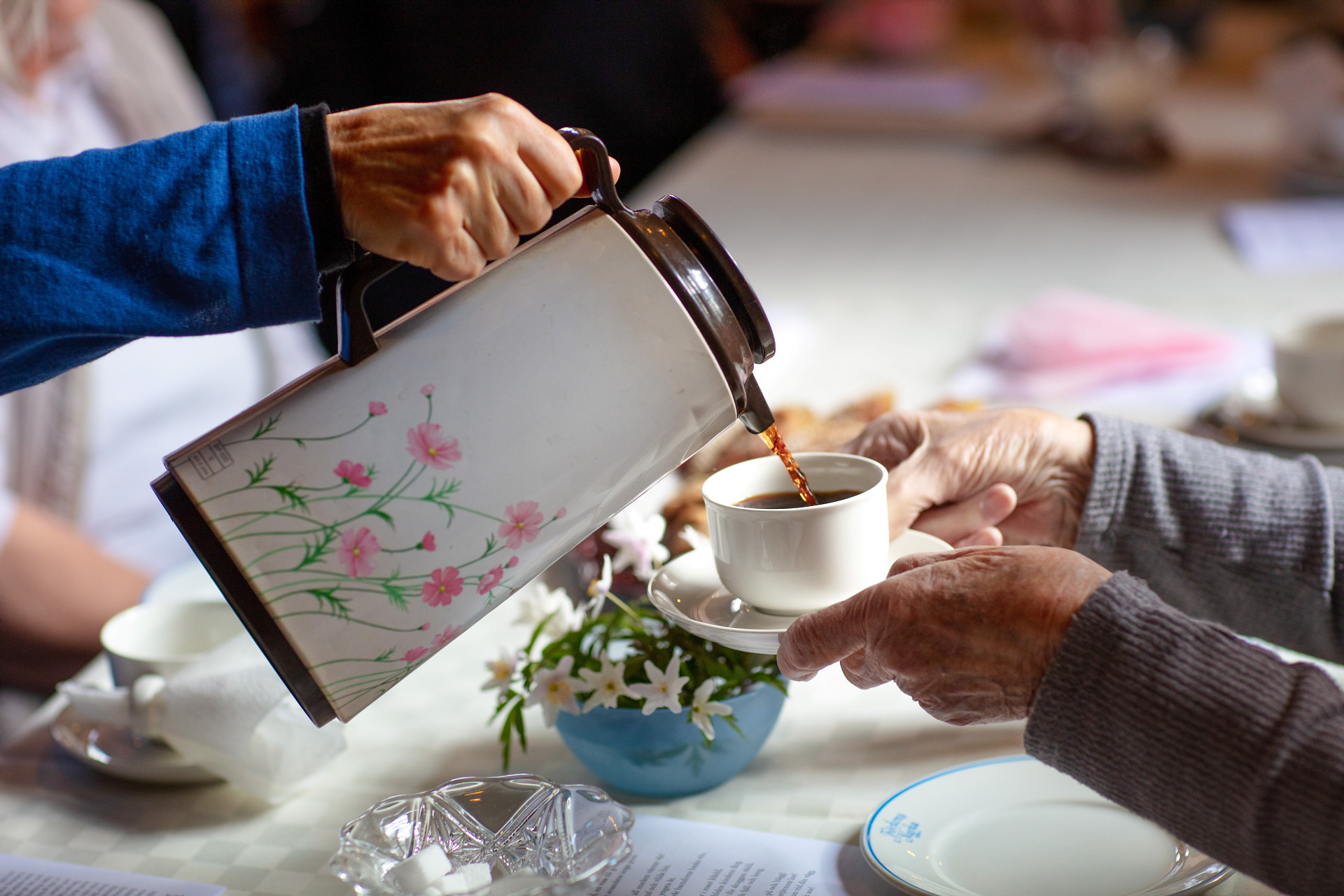 Någon häller upp kaffe ur en blommig termos