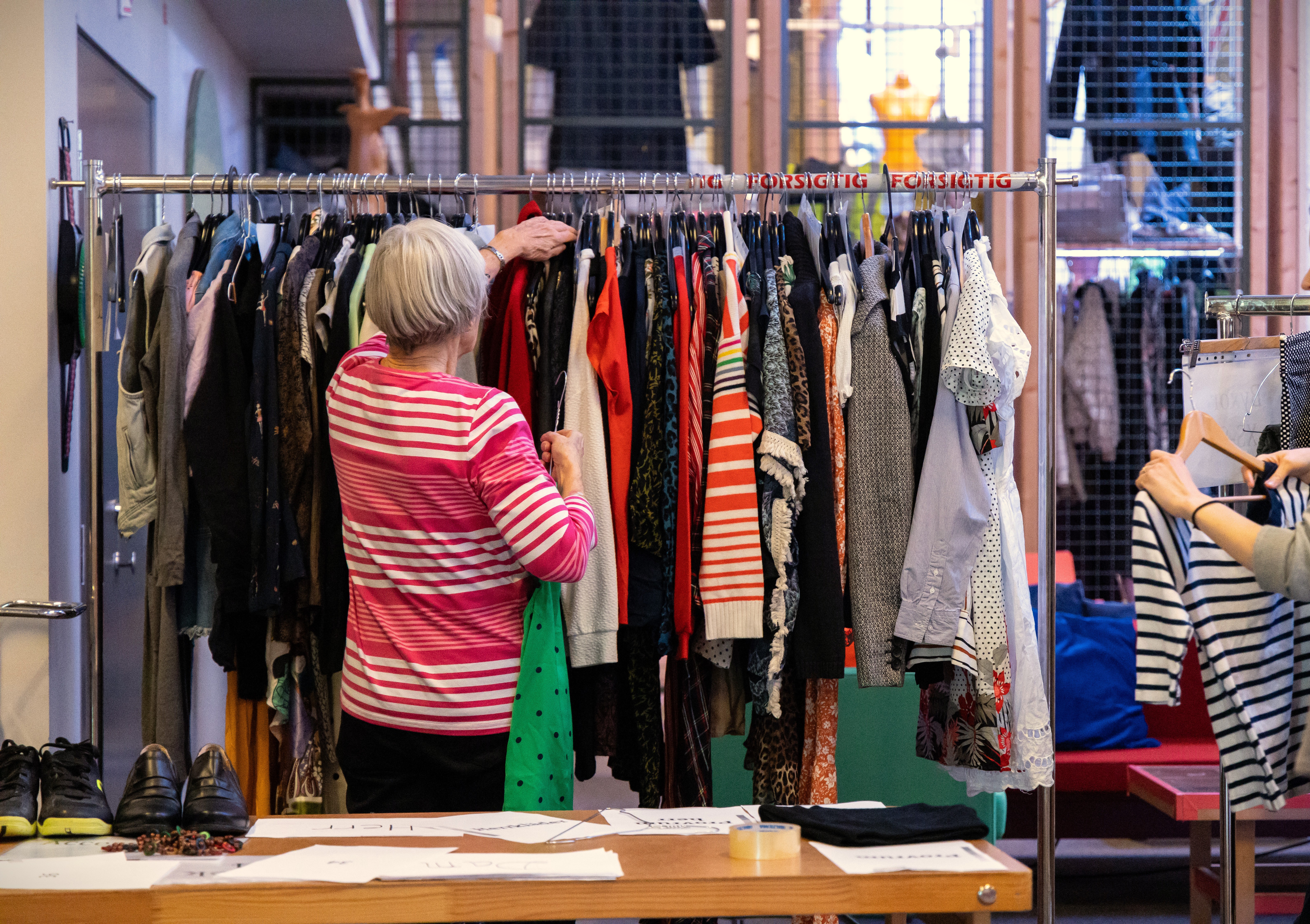 Kvinna tittar på kläder som hänger på ställning.