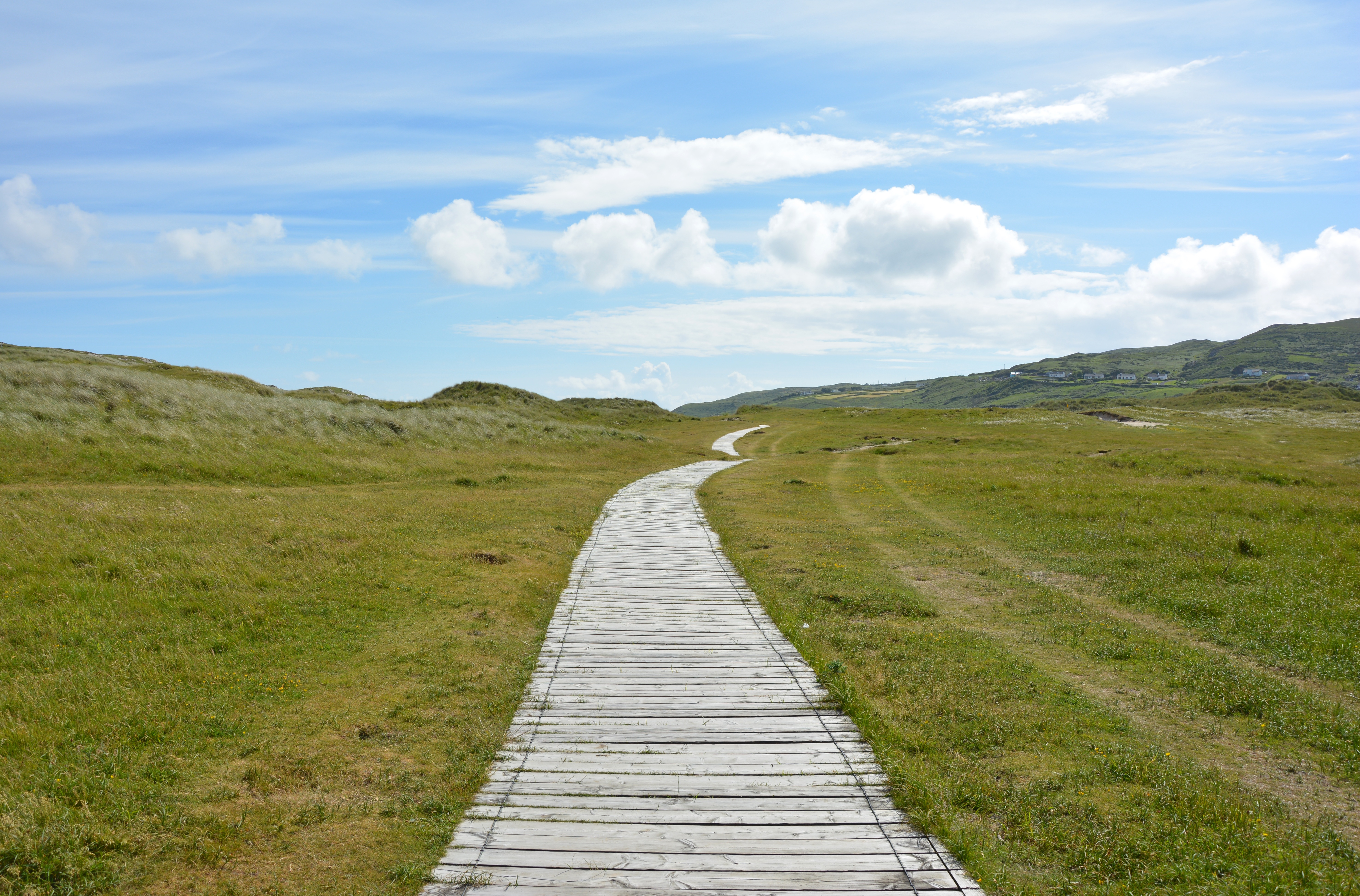 Eng gångväg mot horisonten, blå himmel med vita moln.