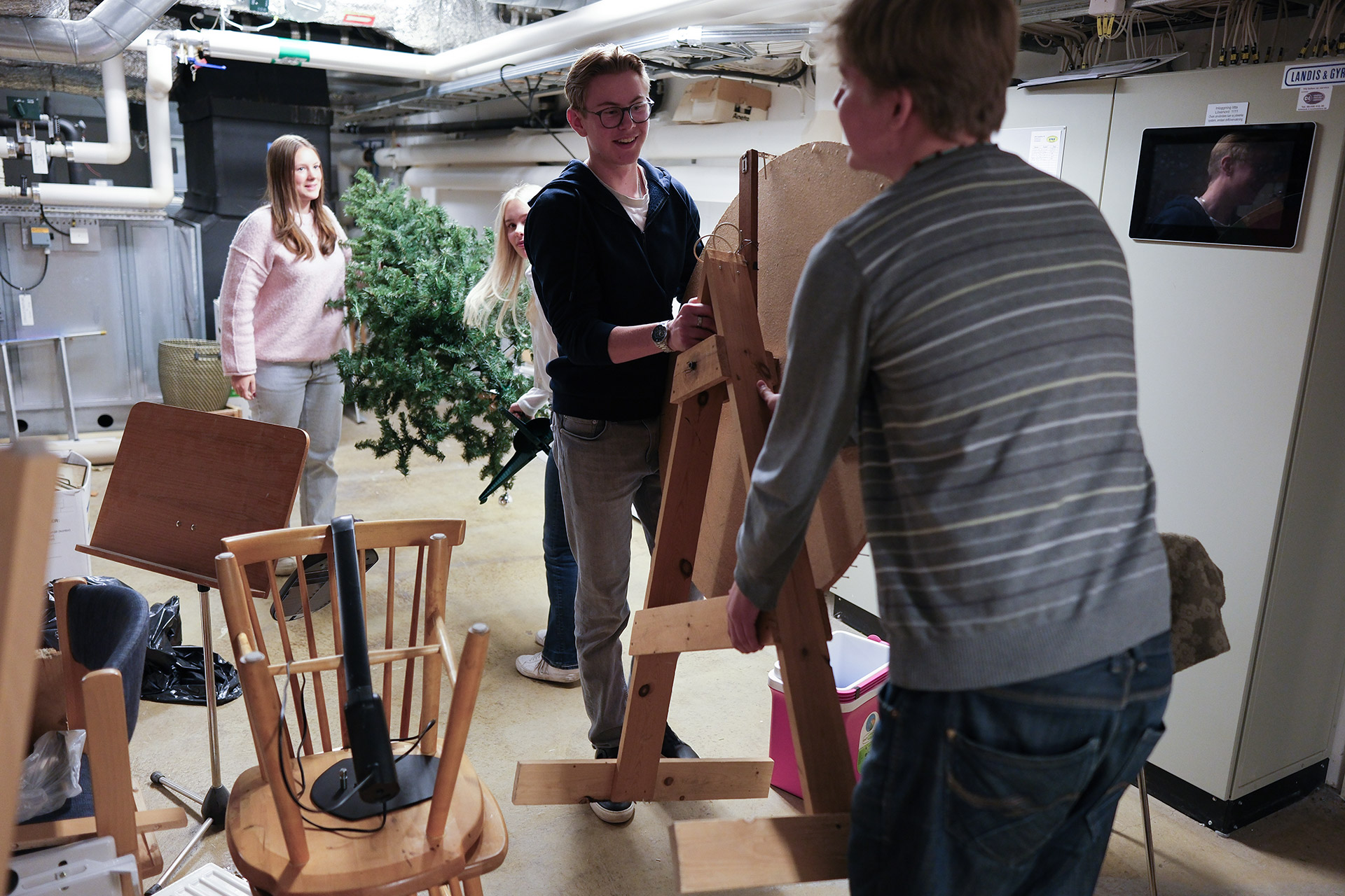 Jakob och Eskil bär upp snurrhjulet från Ängskyrkans källare. Freja och Iris hämtar julgranen.